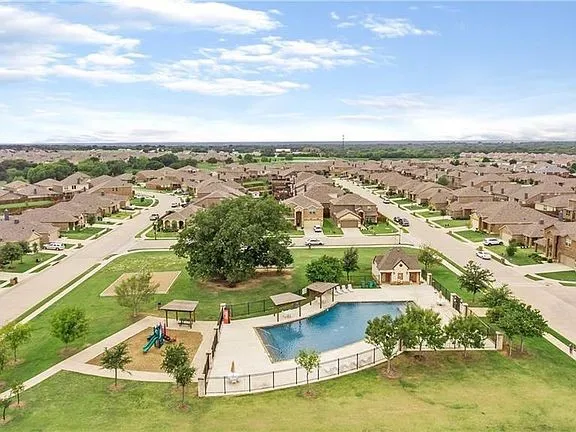 Community pool with fenced perimeter, adjacent clubhouse, and nearby playground