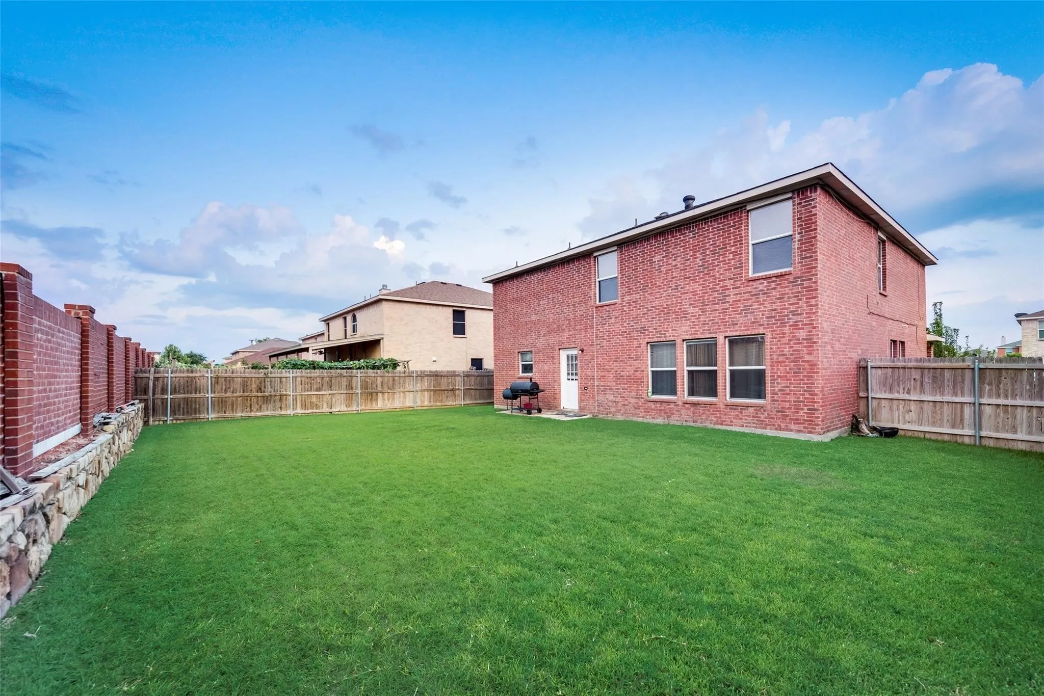 Expansive backyard featuring a manicured lawn, full brick exterior, double-pane windows, and a wood privacy fence