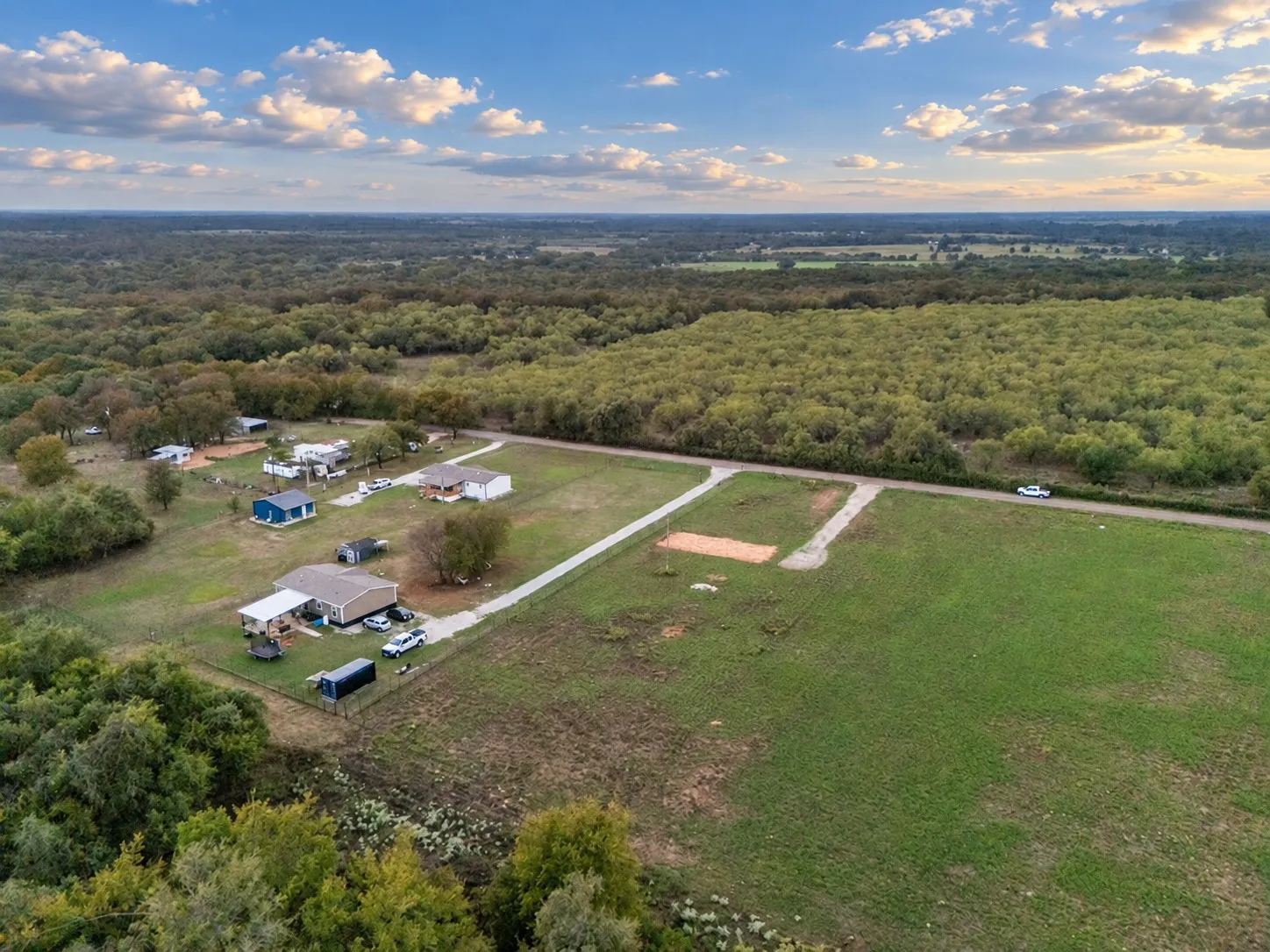 Expansive rural landscape featuring multiple clearings, wooded areas, and a visible roadway