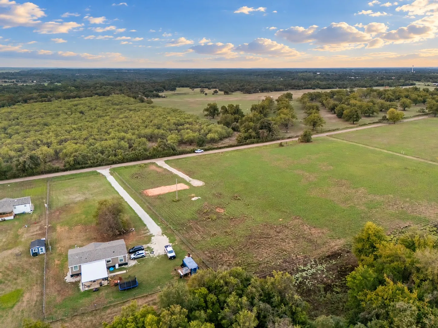 Property featuring expansive green fields, mature trees, and a private road access
