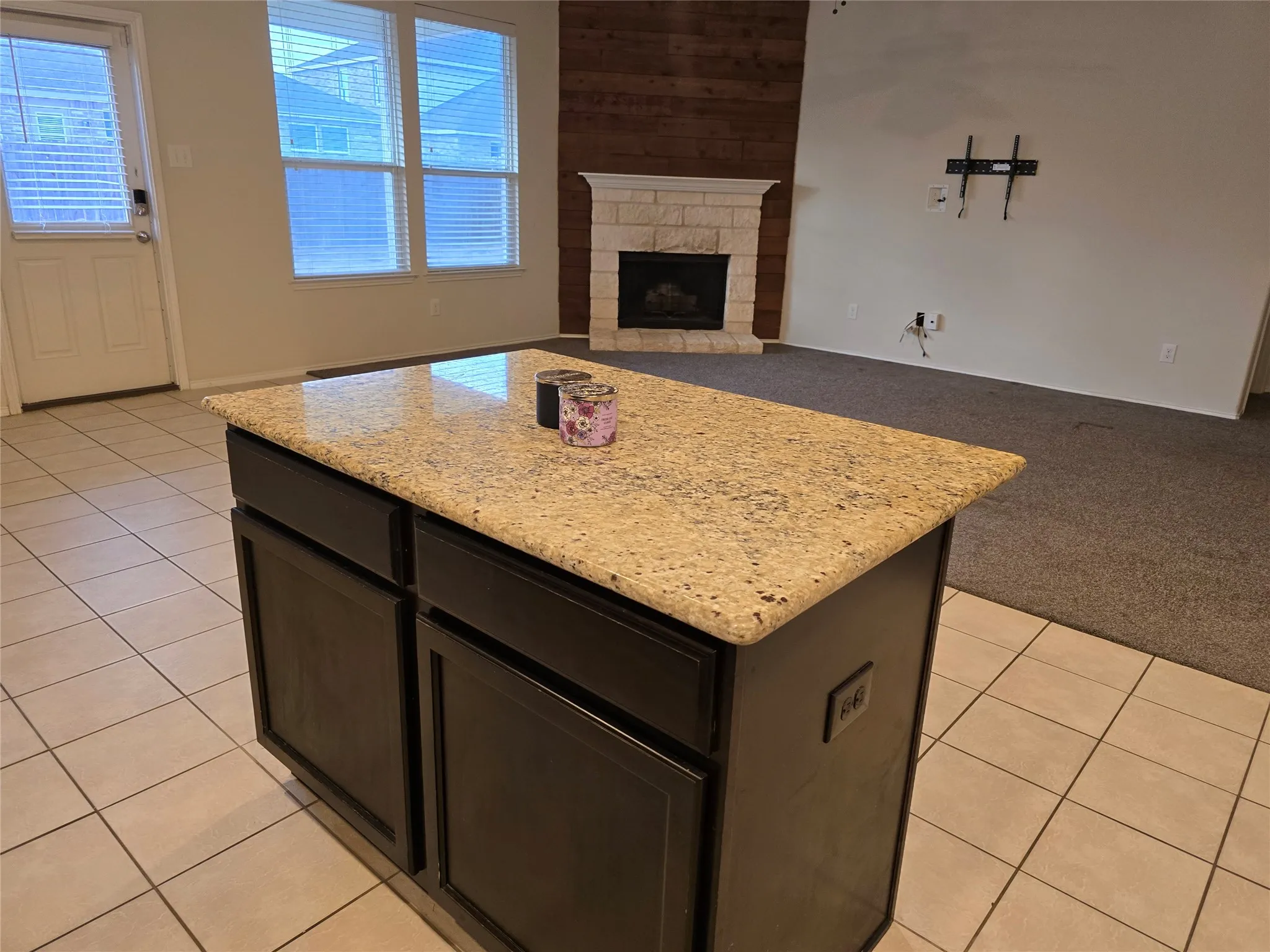 Kitchen island with a light-toned granite countertop and dark wood-finish cabinetry