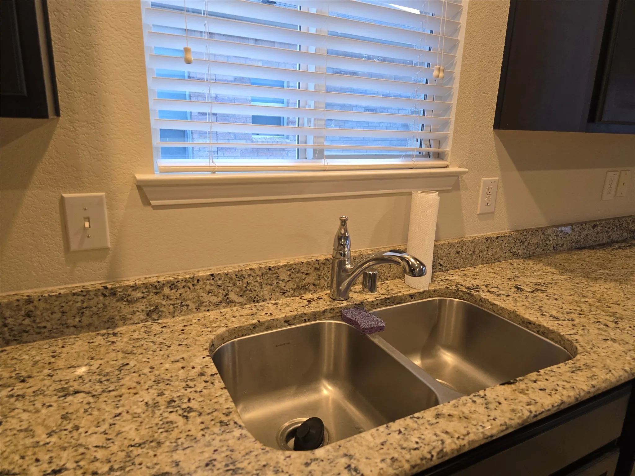 Dual basin stainless steel sink with a chrome faucet, set into a speckled countertop