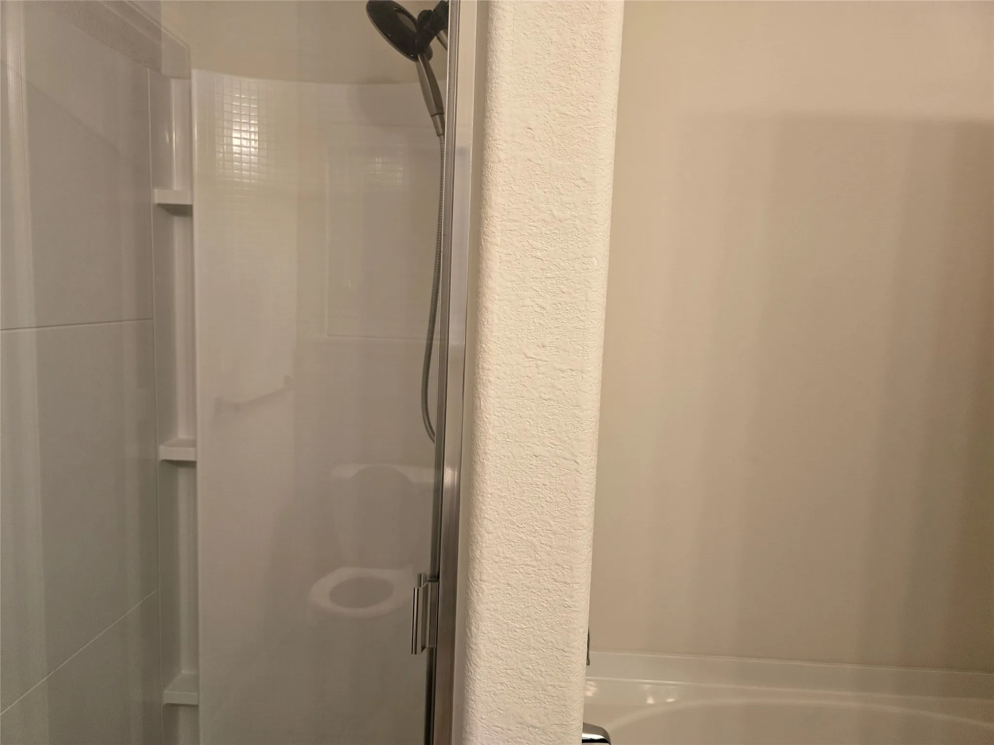 Enclosed shower with a matte black shower head and a built-in shelf