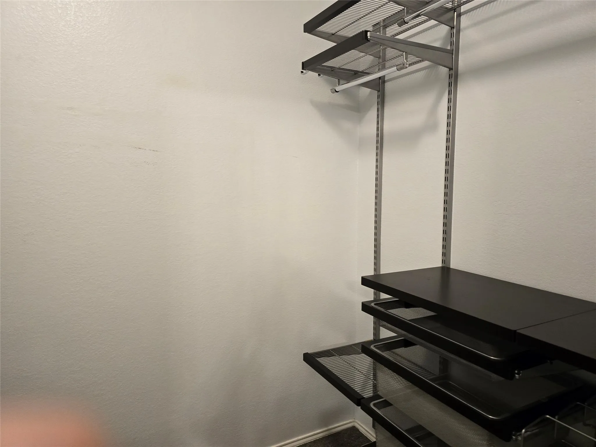 Adjustable shelving system with dark wood-finish shelves and wire pull-out baskets
