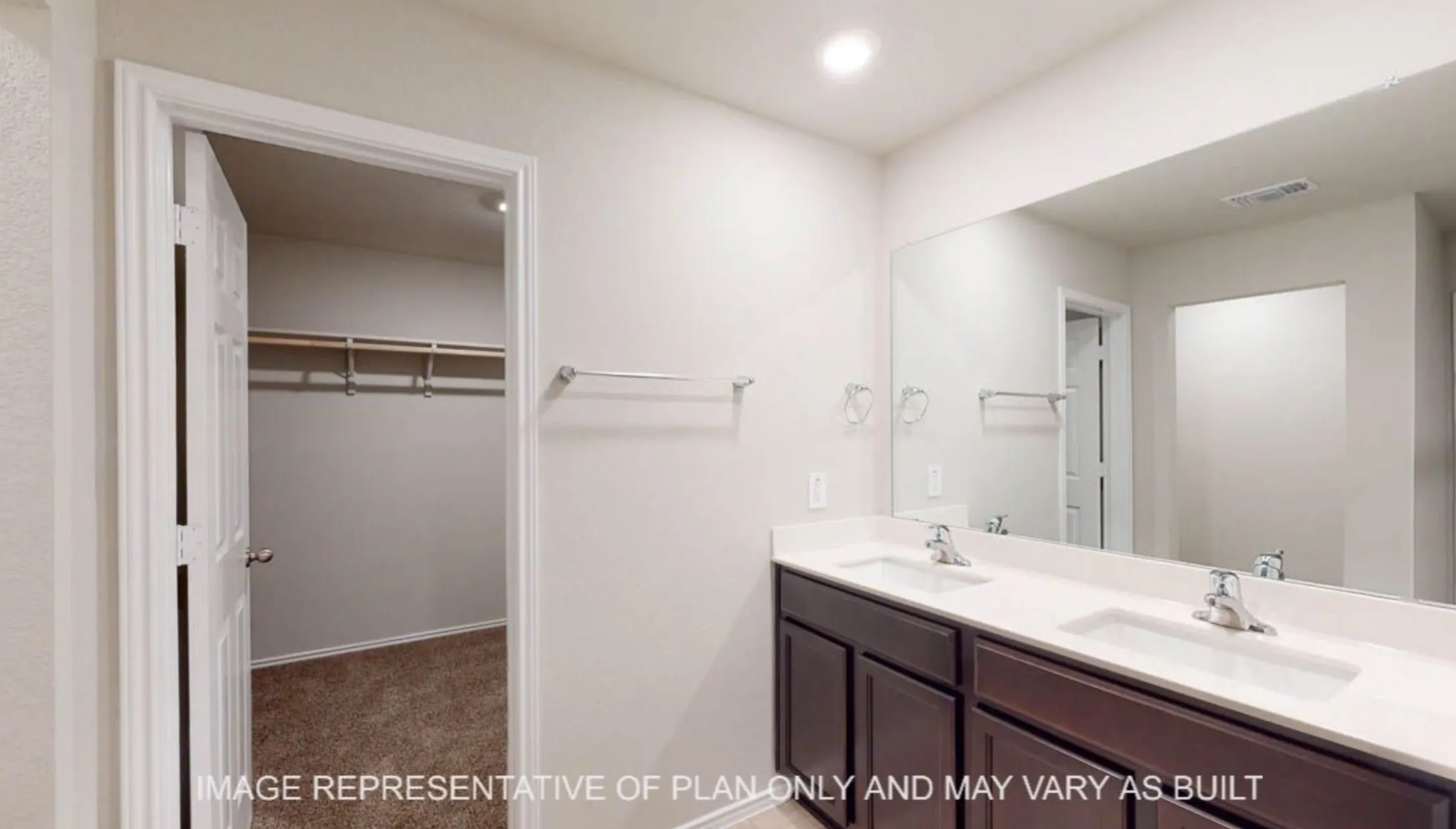 Double vanity with two integrated sinks, expansive wall-mounted mirror, and dark wood-finish cabinetry