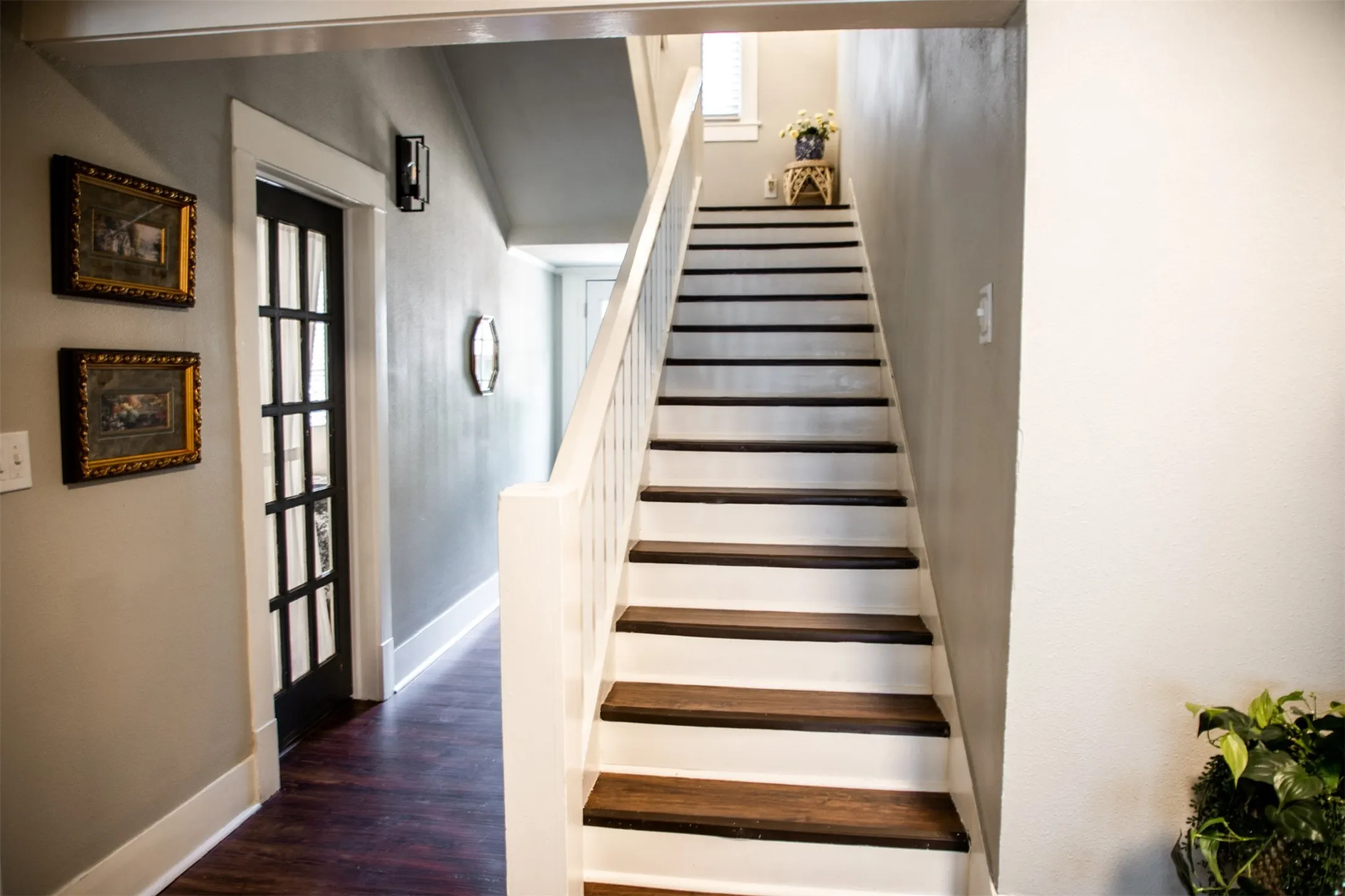 Staircase with wood-finish treads and white risers, featuring a white railing and banister
