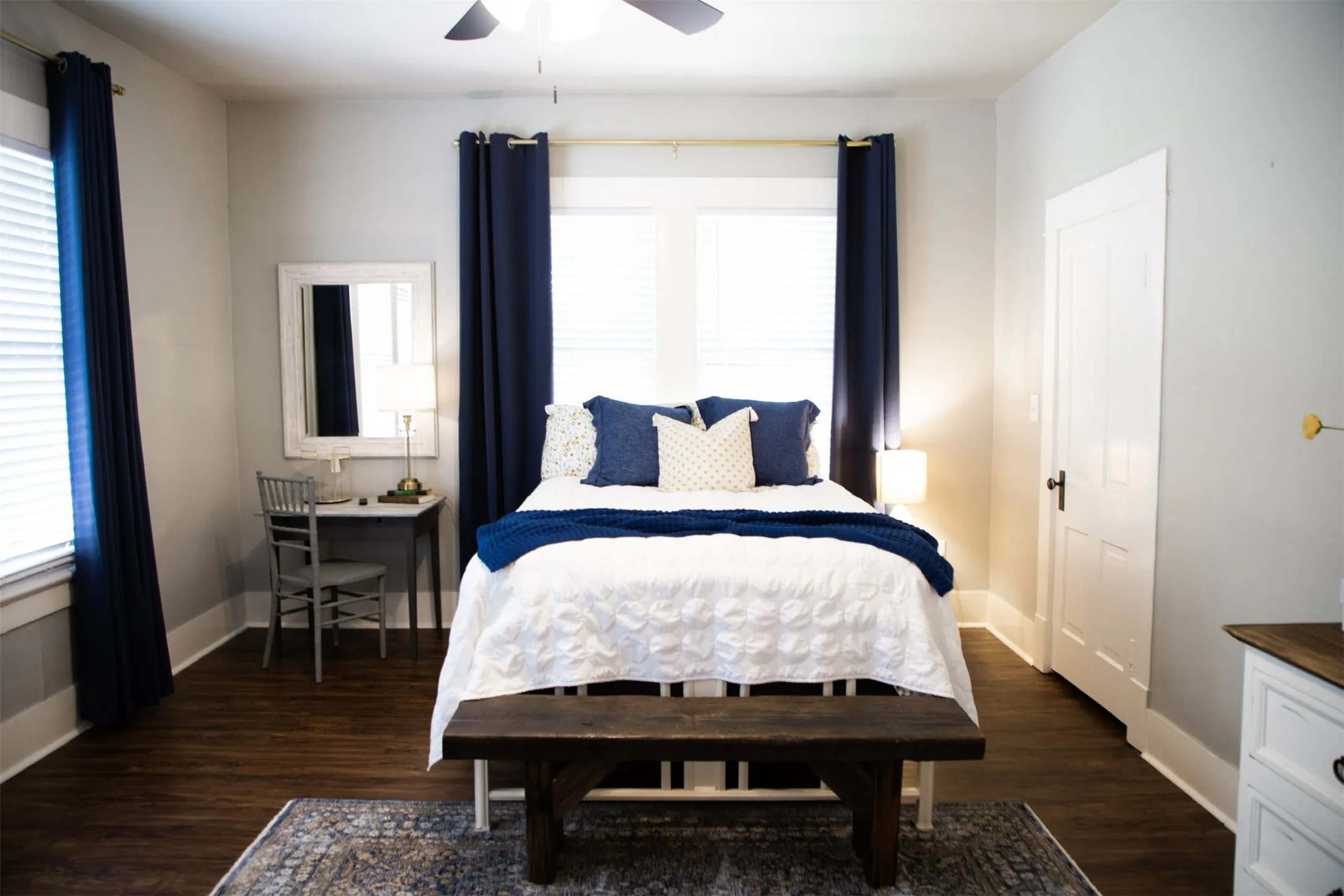 Wood-finish flooring, white trim, and a ceiling fan with integrated lighting