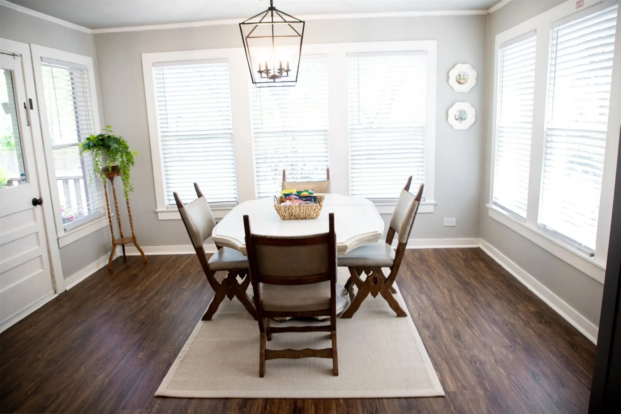 Wood-finish flooring, multiple windows with blinds, and an overhead geometric light fixture