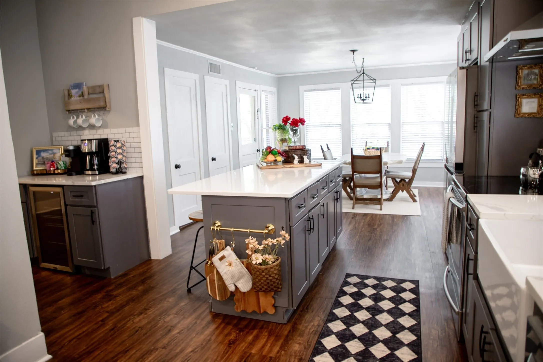 Wood-finish flooring throughout, complemented by a central island with a white countertop and dark cabinetry