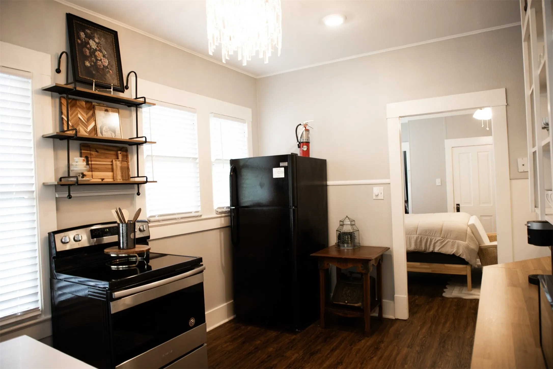 Modern kitchen featuring stainless steel appliances, dark wood-finish flooring, and open shelving