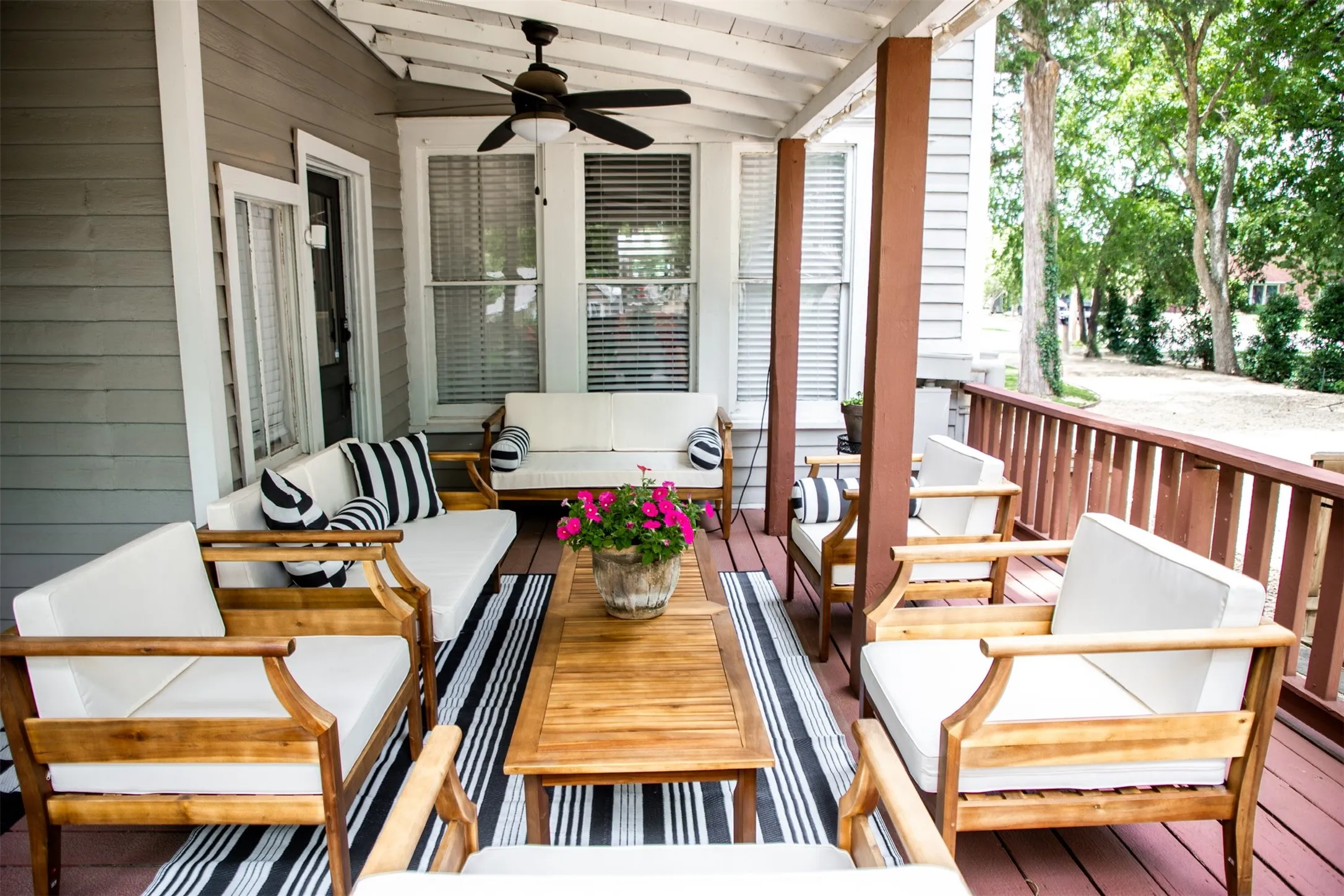 Covered outdoor porch featuring a ceiling fan, wood-finish flooring, and painted wood railings