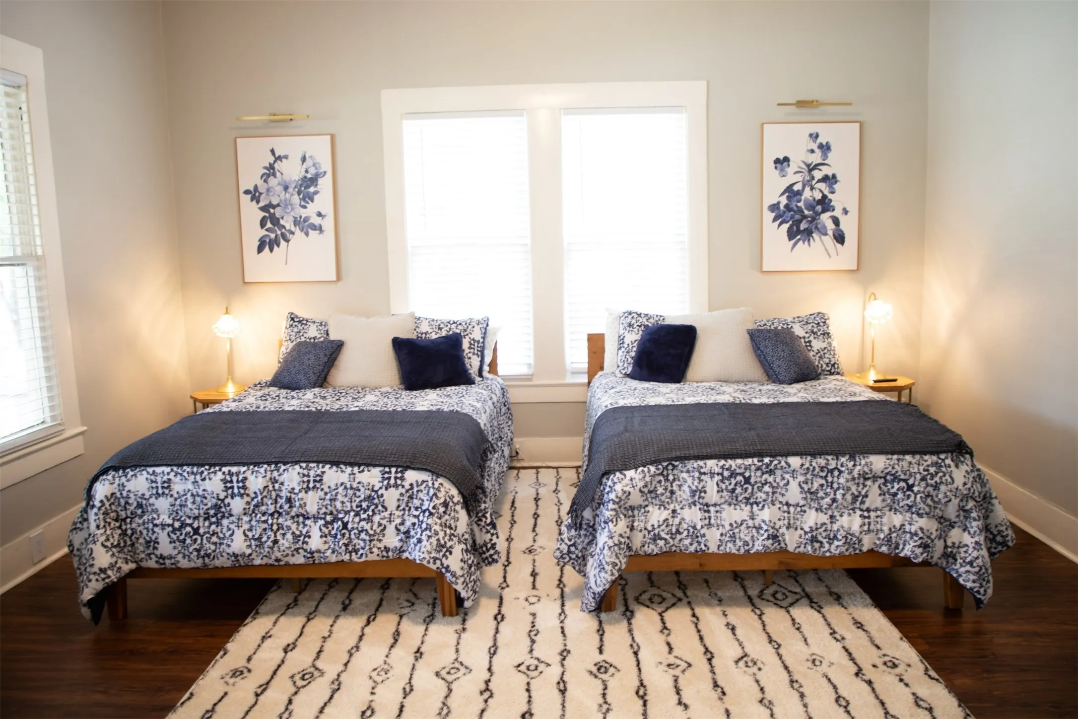 Dual windows with blinds, wood-finish flooring, and light wall paint