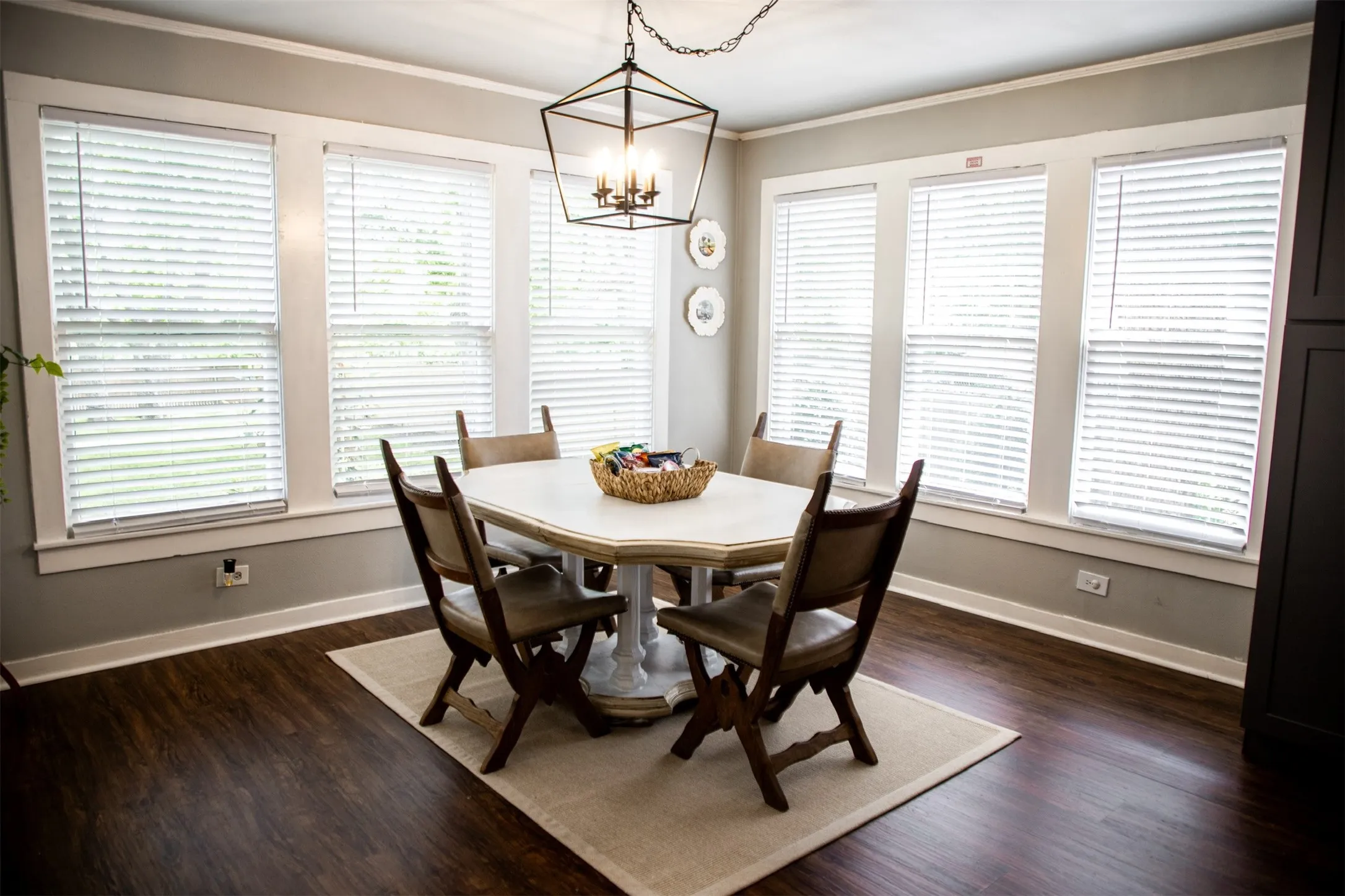 Dark wood-finish flooring, multiple windows with white trim, and a ceiling-mounted light fixture