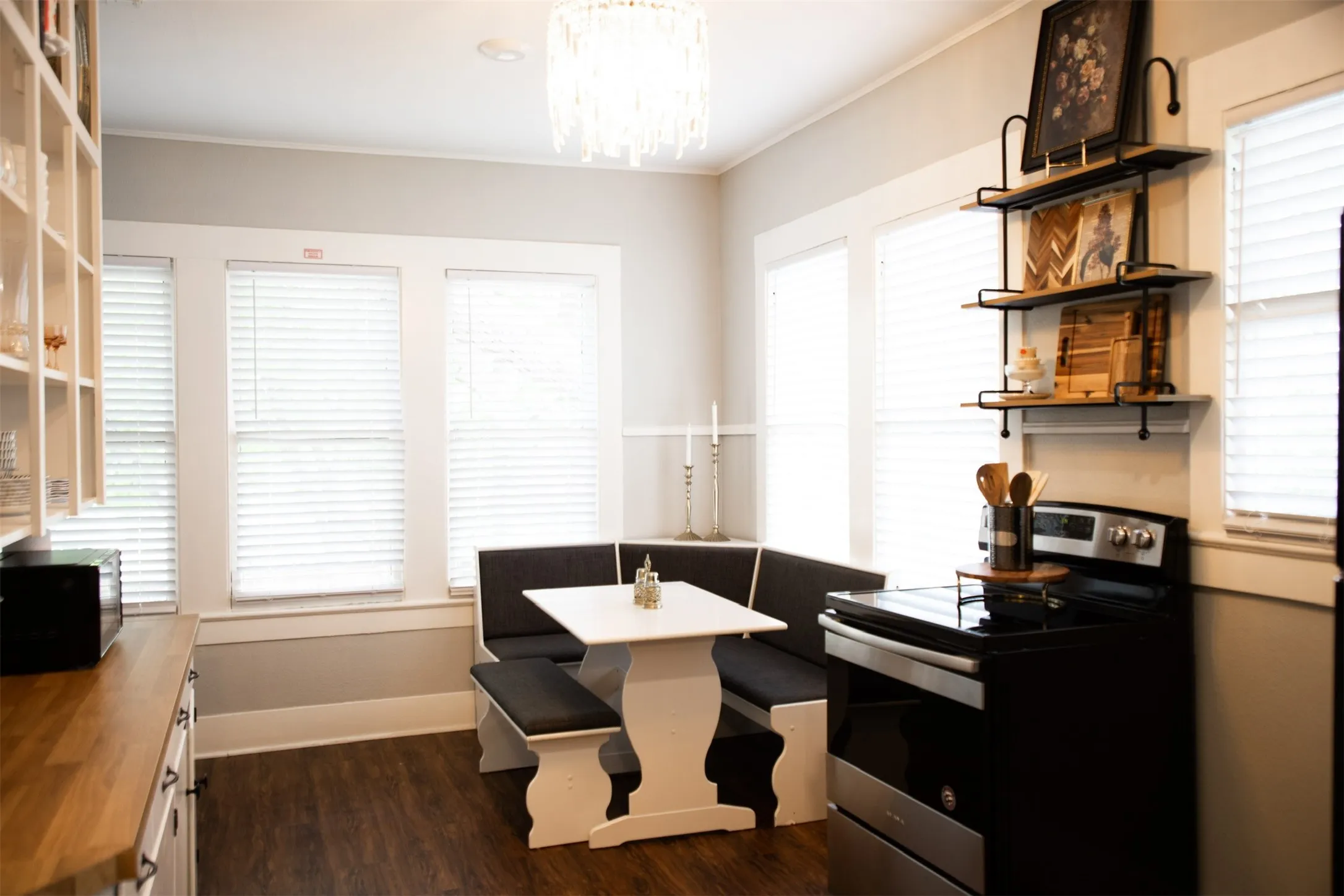 Built-in banquette seating with a white table, pendant light fixture, wood-finish flooring, and open shelving