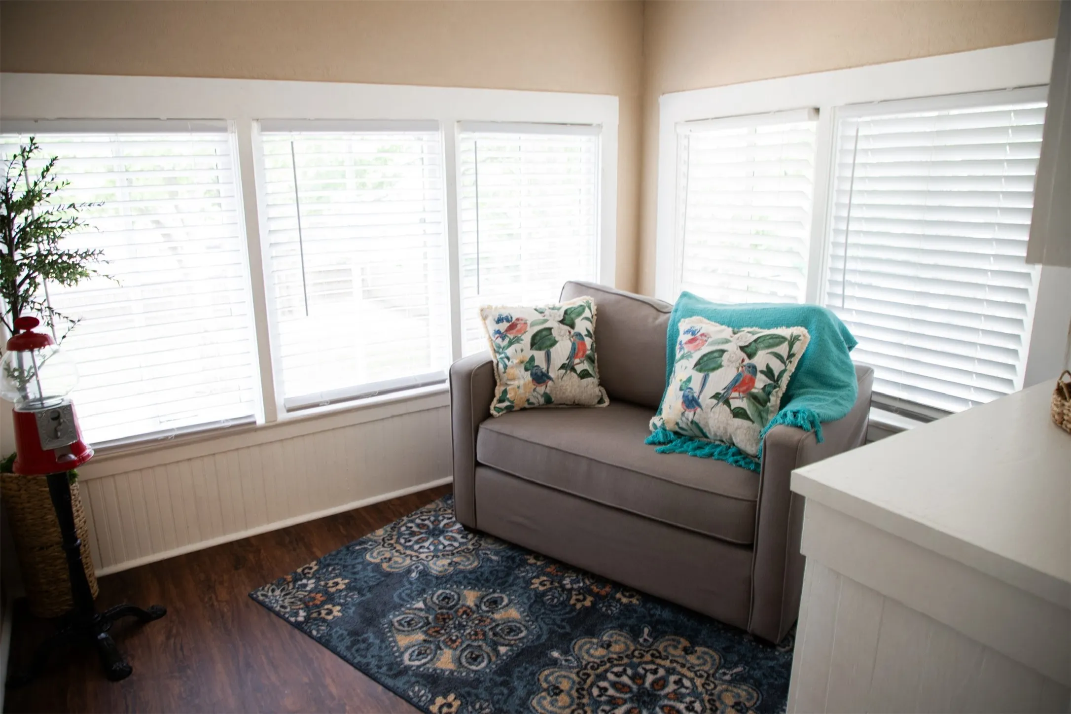 Wood-finish flooring, multiple windows with blinds, and white wainscoting