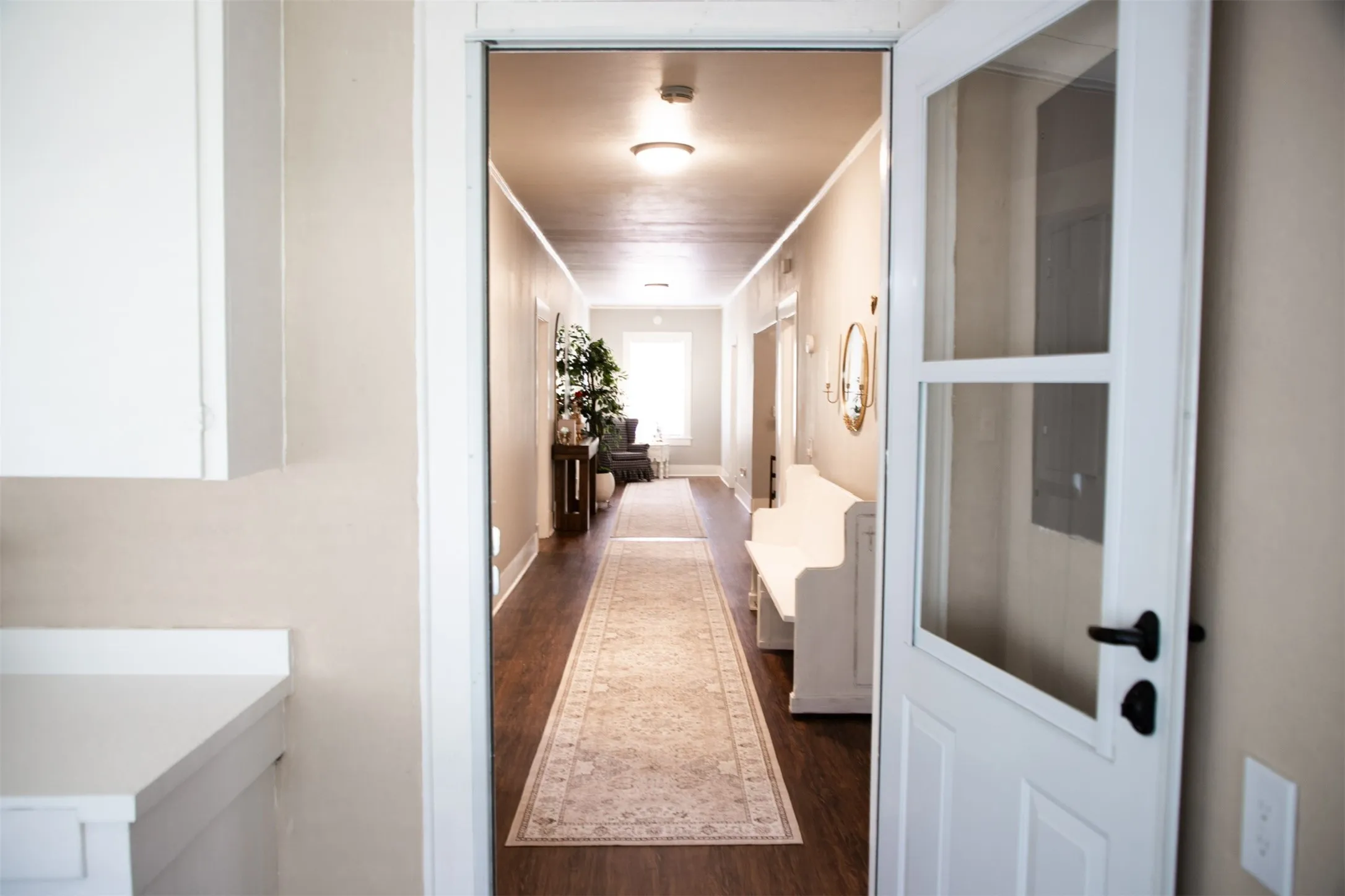 White cabinetry, light countertop, glass-paneled interior door, wood-finish flooring, and recessed lighting