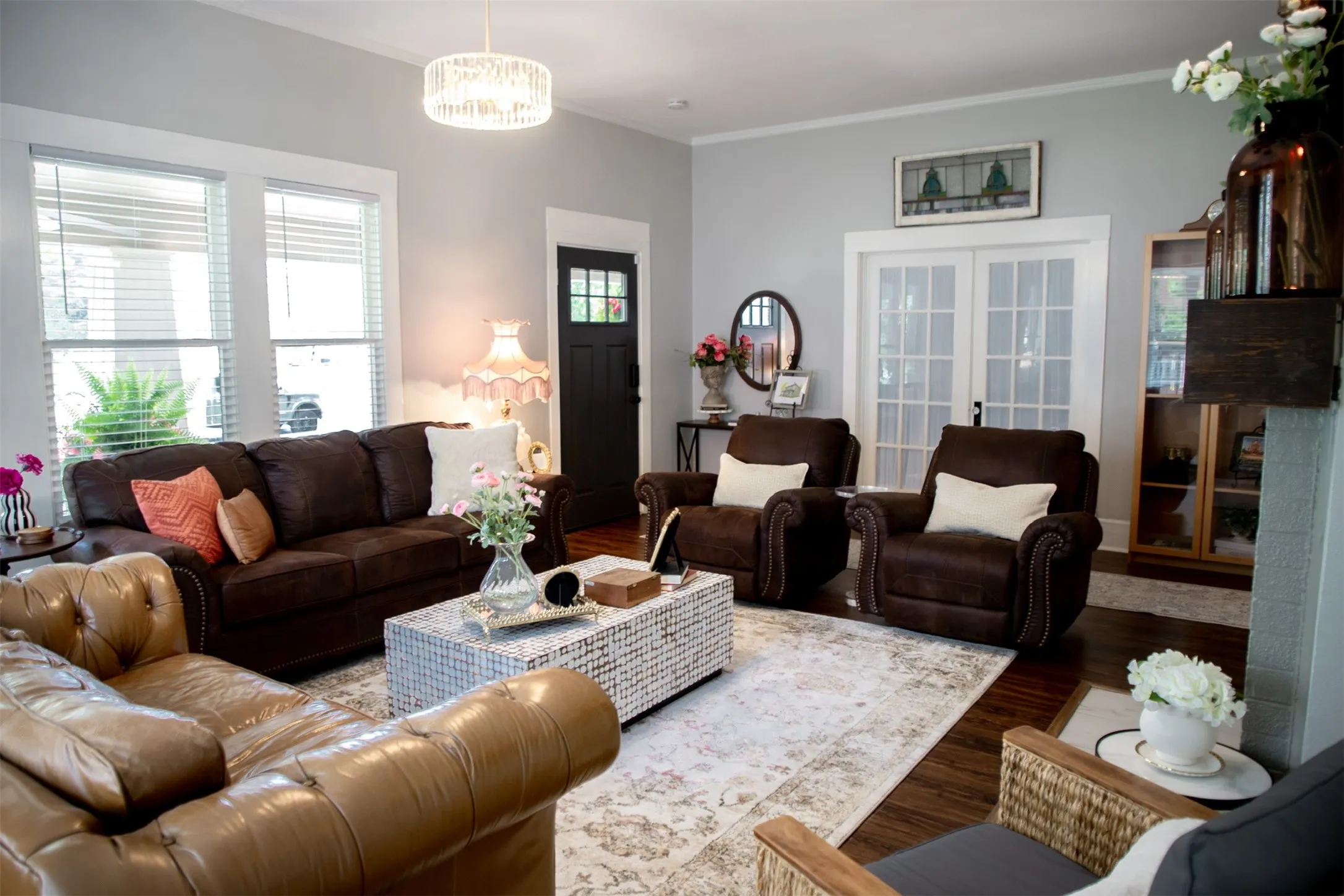 Hardwood flooring, crisp white trim, double French doors, large windows, and an ornate ceiling light fixture