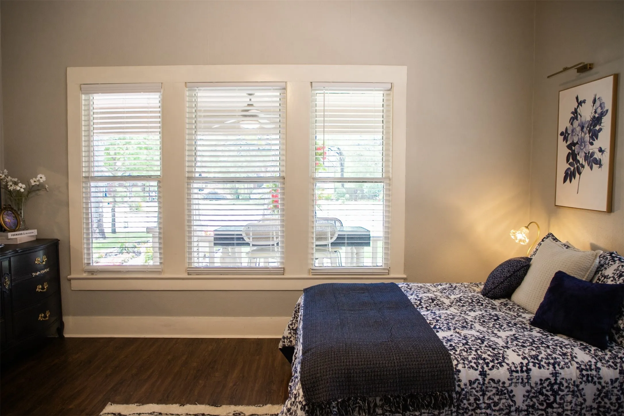 Triple window unit with white blinds, wood-finish flooring, and neutral wall paint