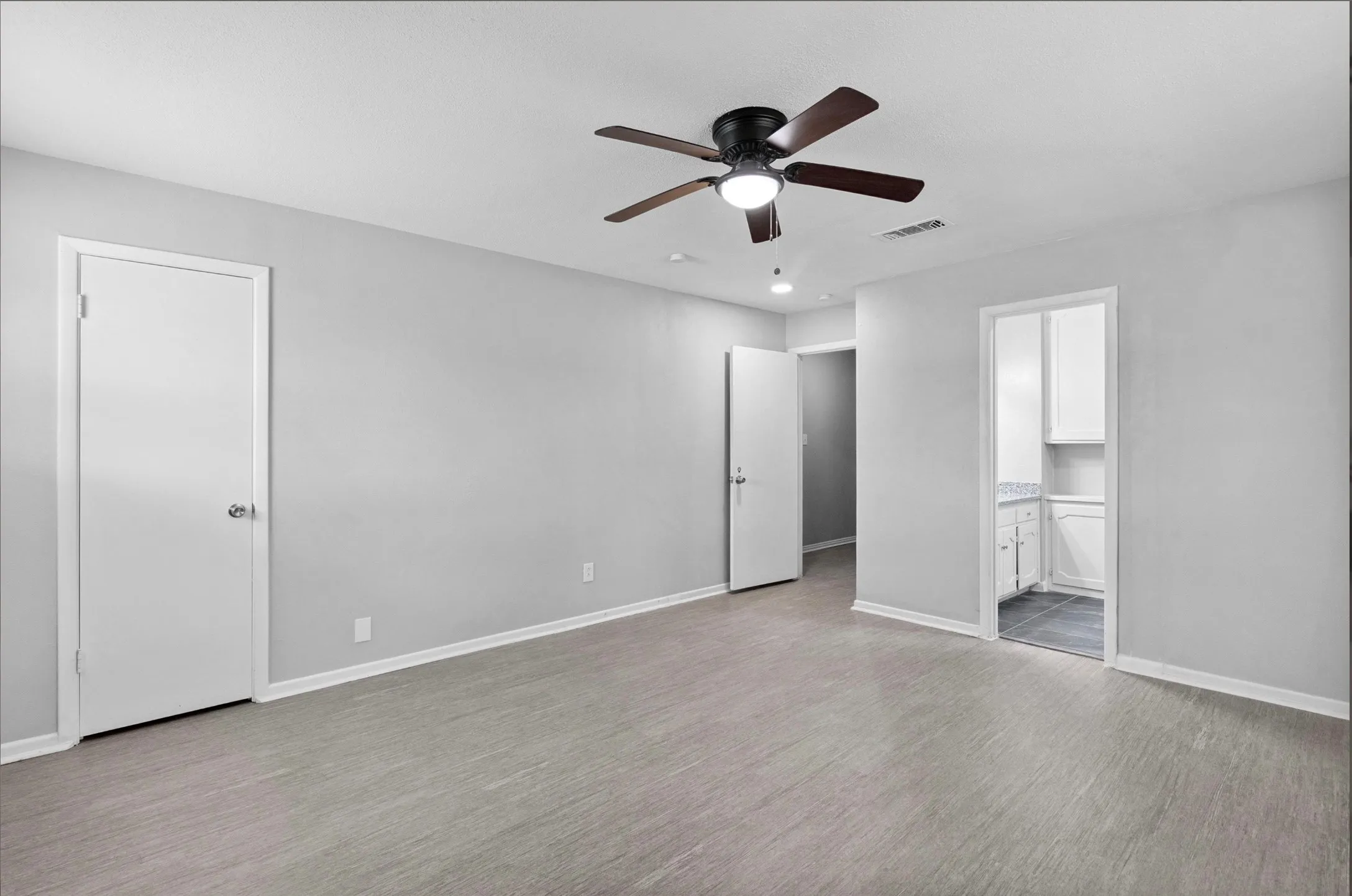 Wood-finish flooring, ceiling fan with integrated lighting, and white trim throughout