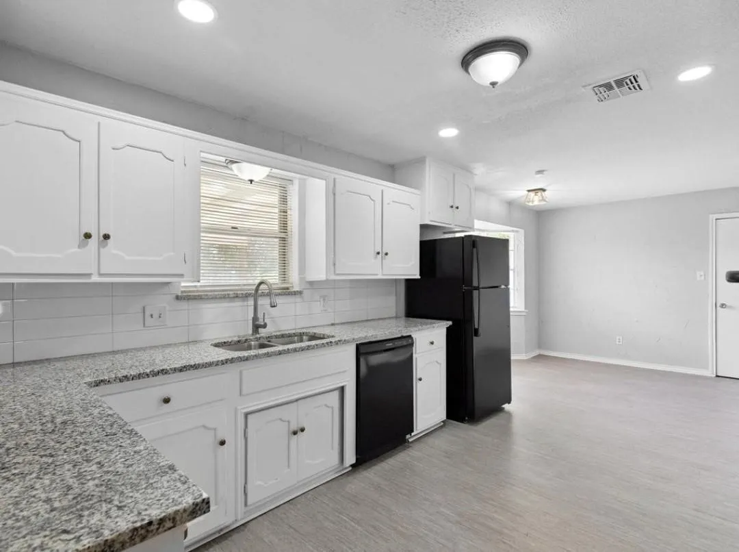 White cabinetry, granular countertops, white subway tile backsplash, stainless steel sink with gooseneck faucet, and wood-finish flooring