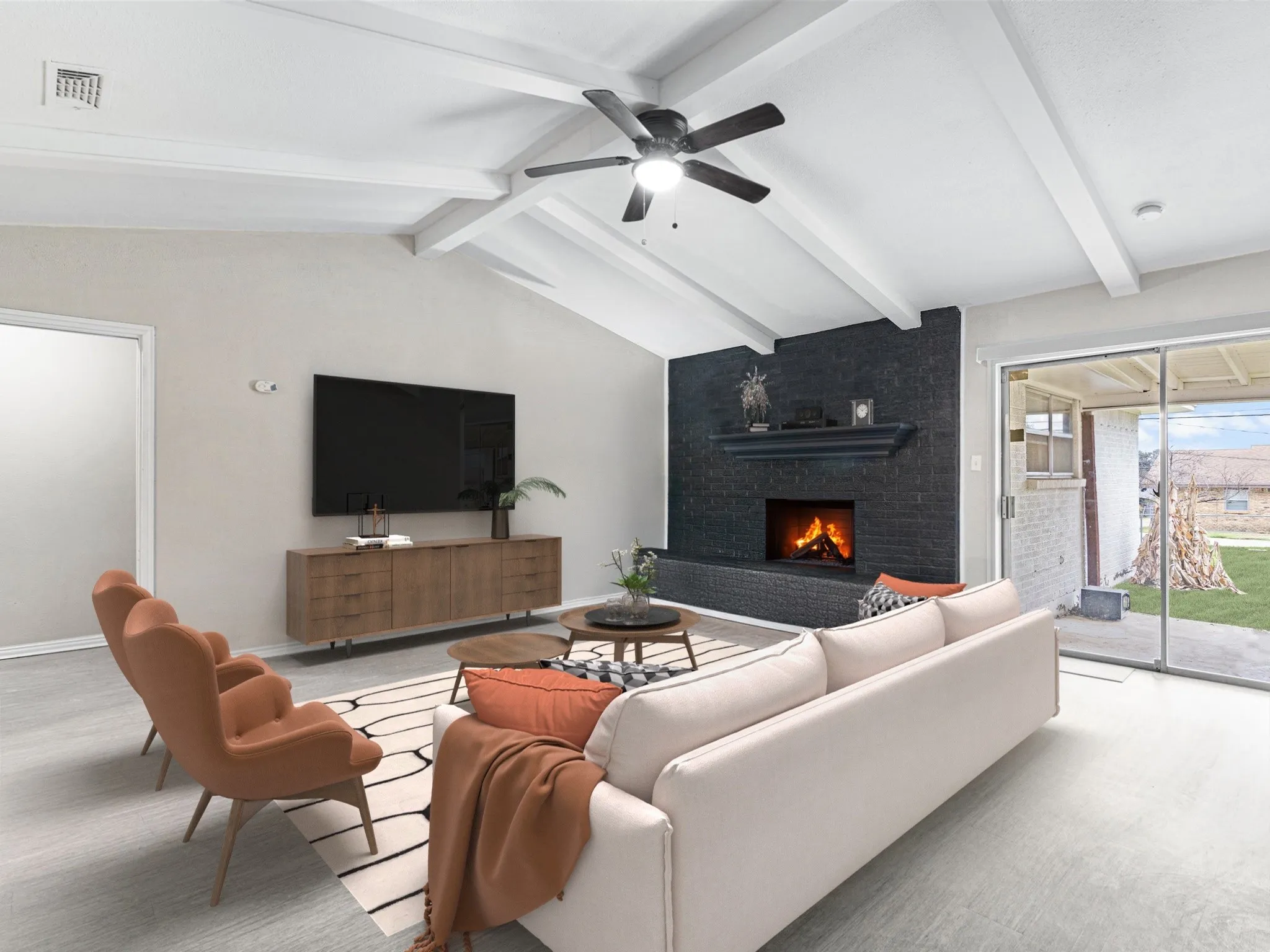 Vaulted ceiling with exposed beams, brick fireplace with mantel, ceiling fan with integrated lighting, sliding glass door, and light wood-finish flooring