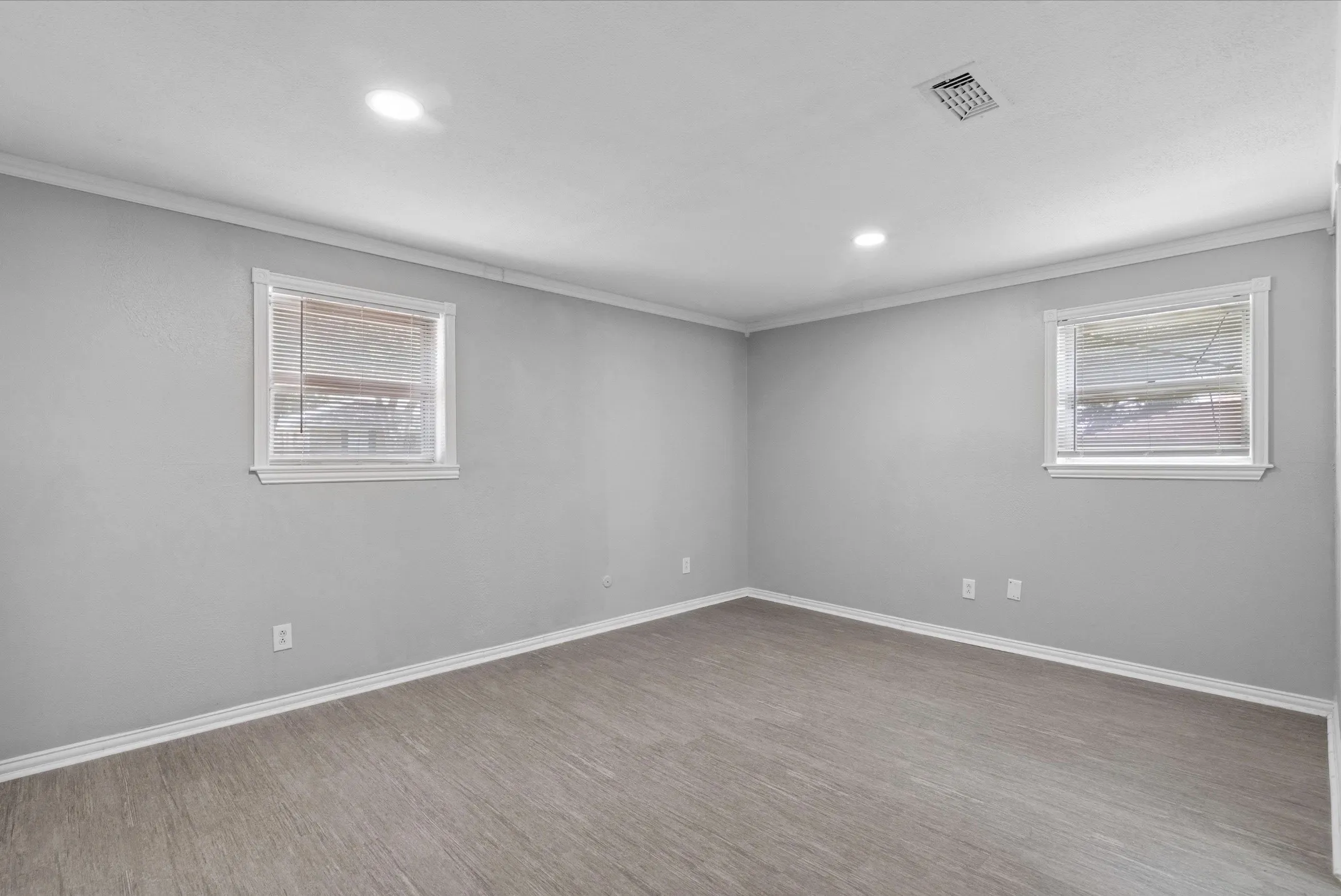 Wood-finish flooring, recessed lighting, crown molding, and two windows with blinds