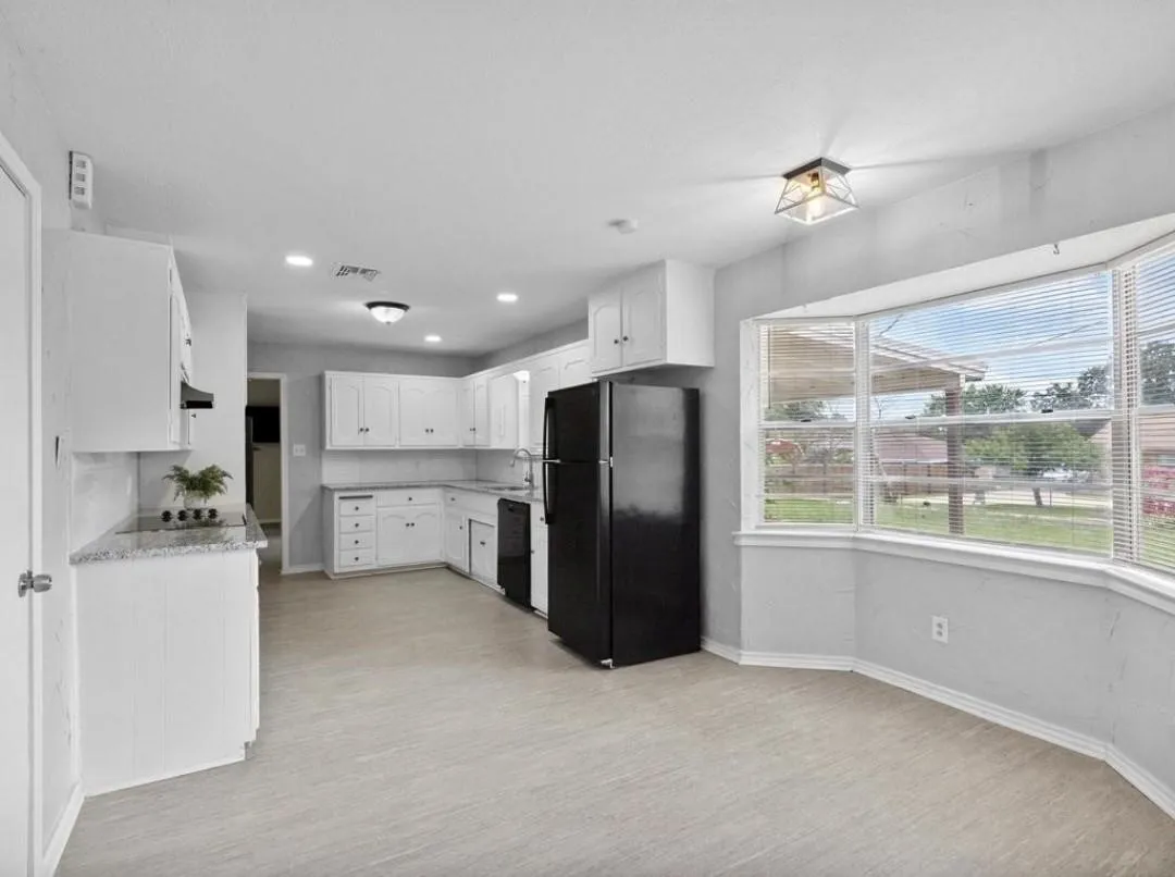 Kitchen featuring white cabinetry, light-toned flooring, and speckled countertops