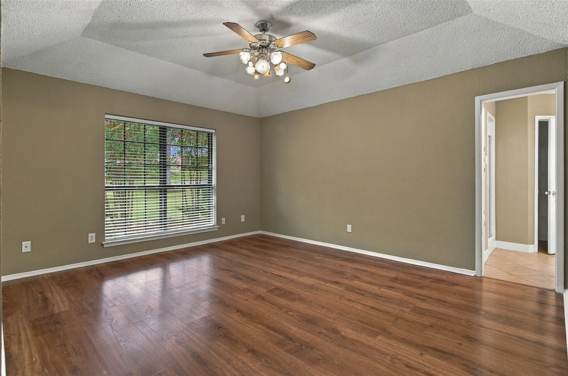 Tray ceiling with a ceiling fan, LVP flooring, and a large window