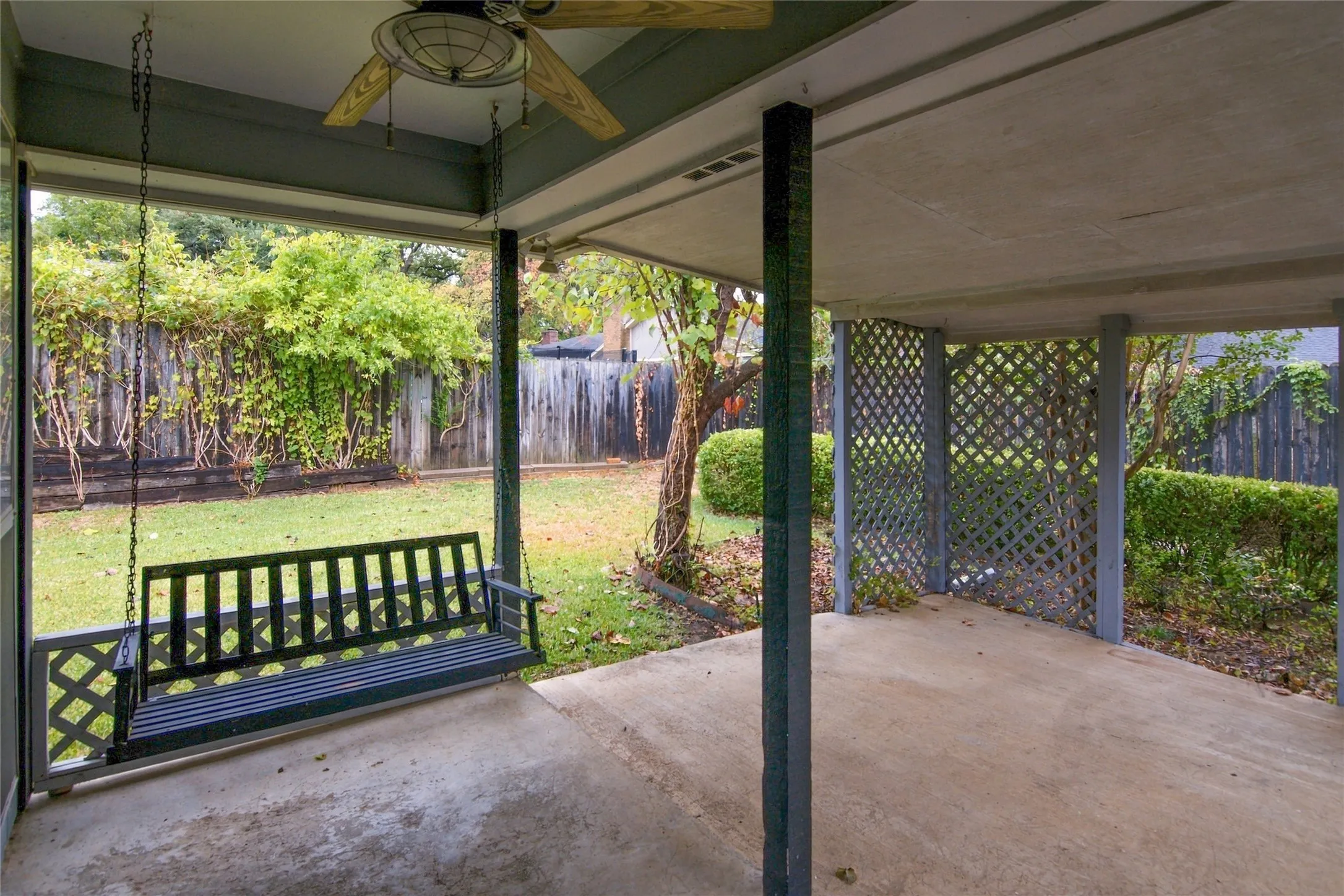 Covered patio with concrete flooring, swing for outdoor relaxing and ceiling fan