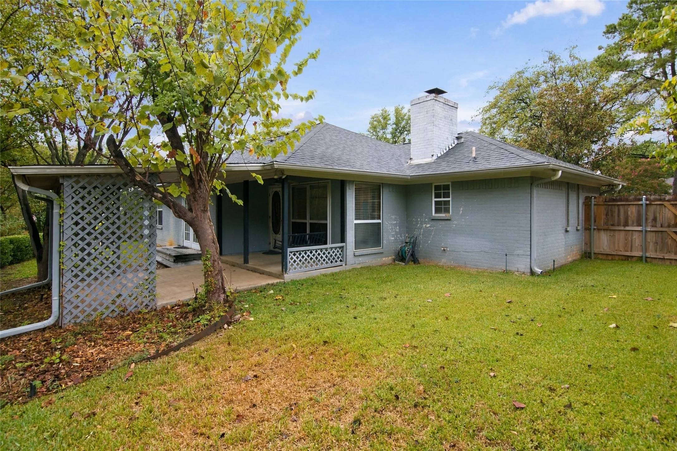 Expansive backyard featuring a manicured lawn, wood privacy fencing and covered patio area