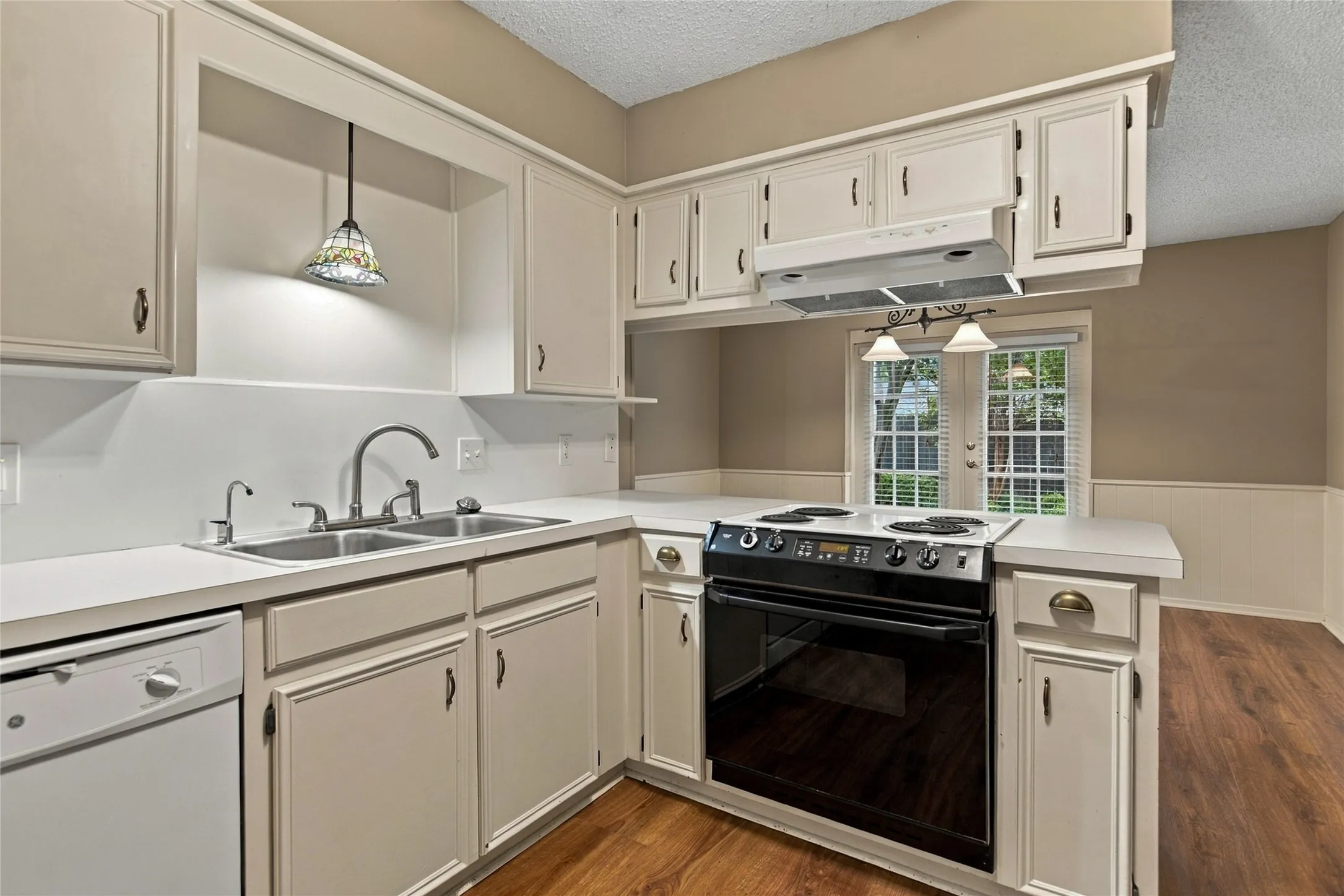 White cabinetry , stainless steel double sink, black electric range with overhead ventilation, and LVP flooring