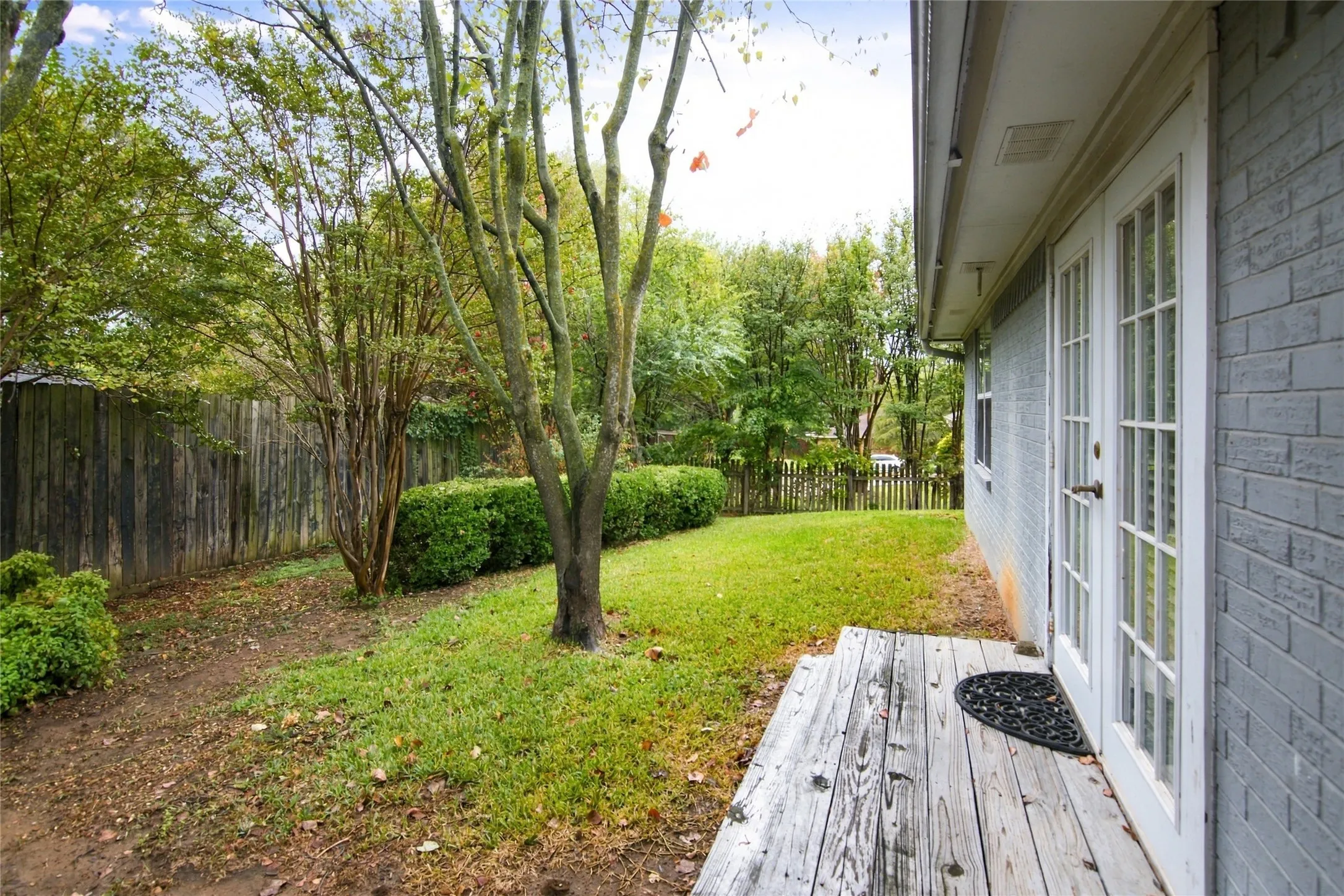 Expansive backyard featuring a manicured lawn, established trees, and a privacy fence