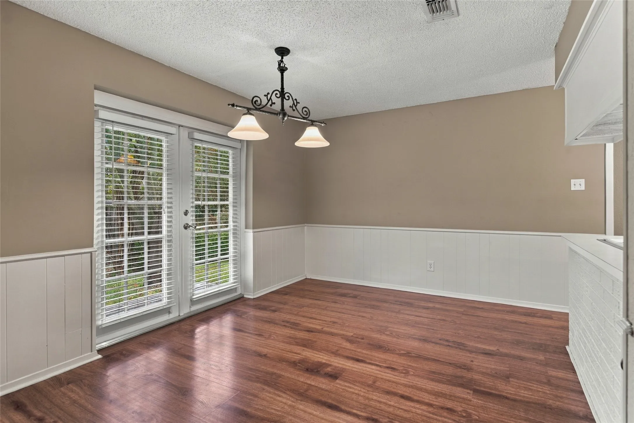 French doors, LVP flooring, white panel wainscoting, and a ceiling light fixture