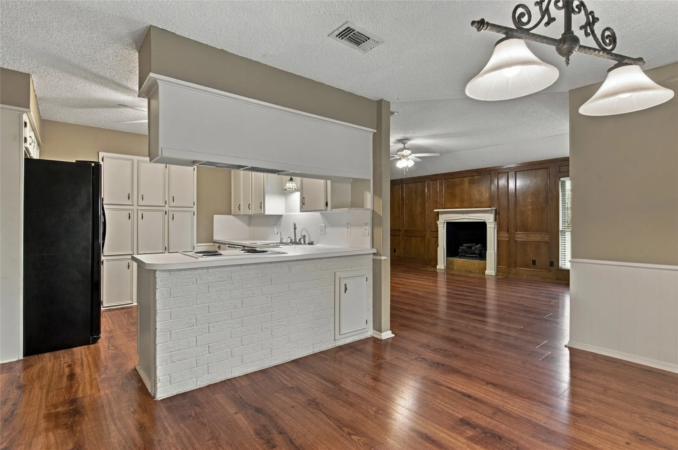 LVP flooring throughout the kitchen with white cabinetry and brick-finish island