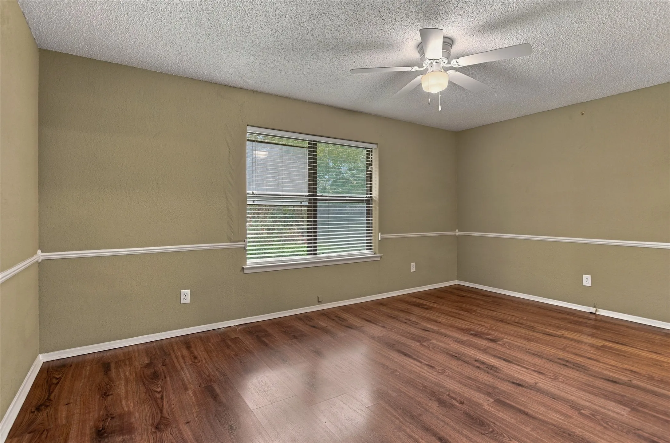 LVP flooring with baseboard trim, neutral wall color, single window with blinds, and ceiling fan with light fixture
