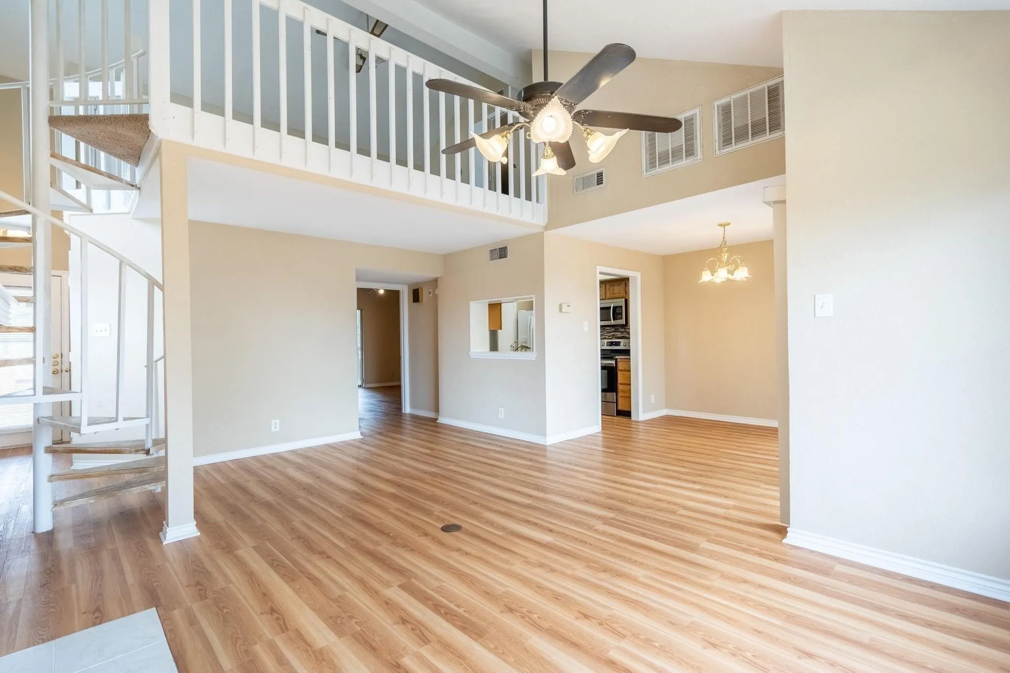 High ceilings with an exposed loft space, wood-finish flooring, and a spiral staircase