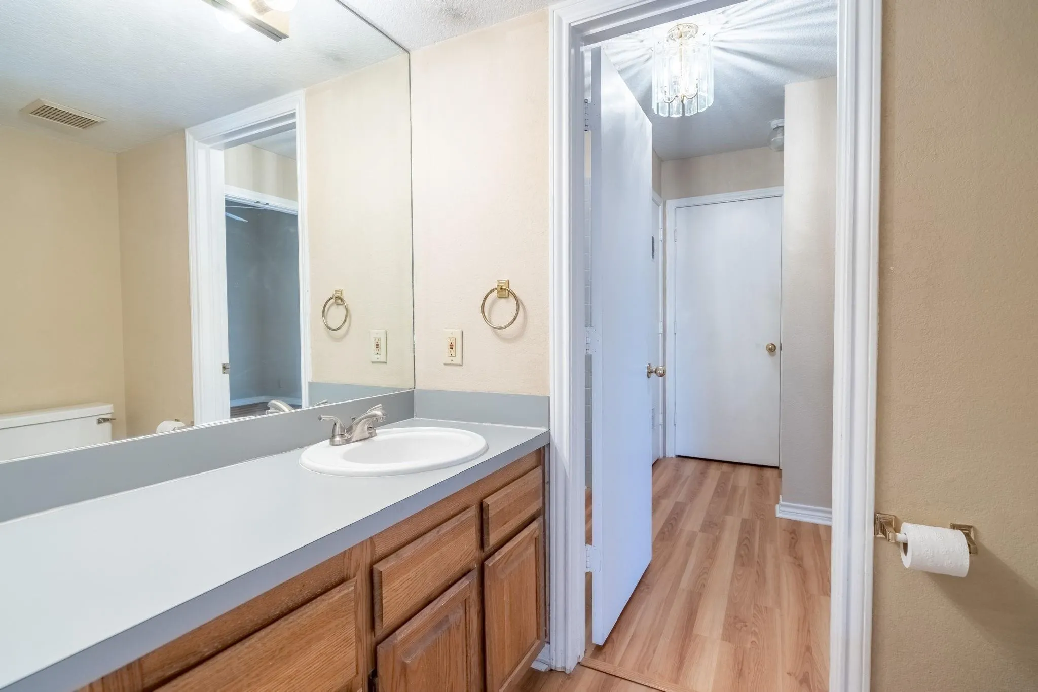Vanity with an integrated white sink, brushed nickel faucet, and wood-finish cabinetry