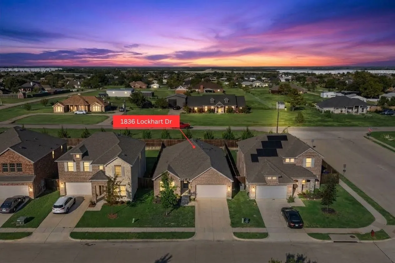 Drone perspective of a residential street with an asphalt roof and a concrete driveway