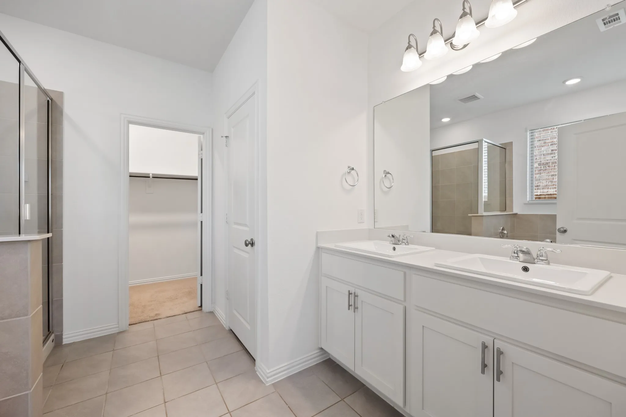 Dual vanity with white cabinetry, integrated sinks, chrome hardware, and a large mirror