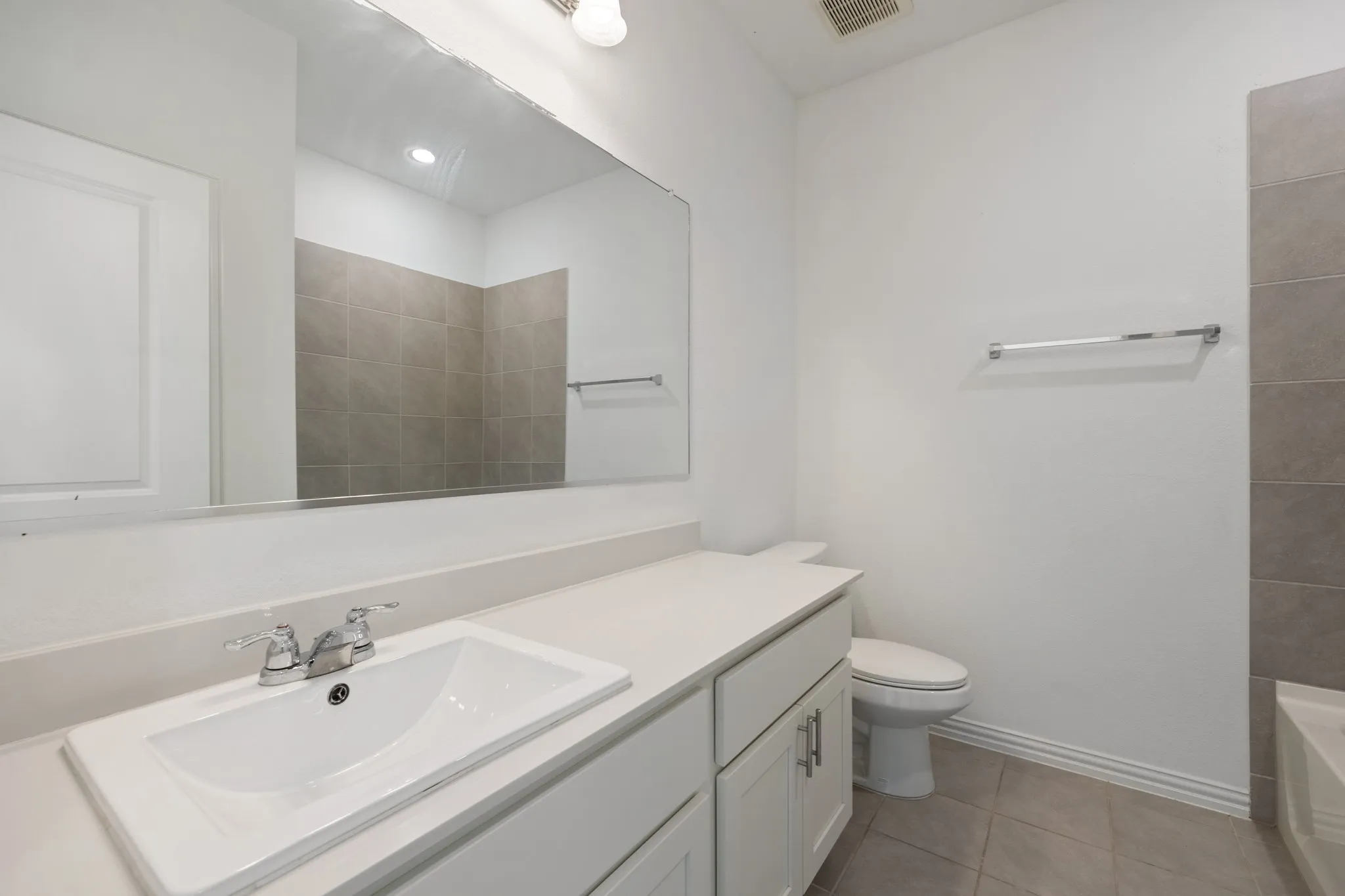 White vanity with a built-in rectangular sink, chrome faucet, and expansive wall-mounted mirror