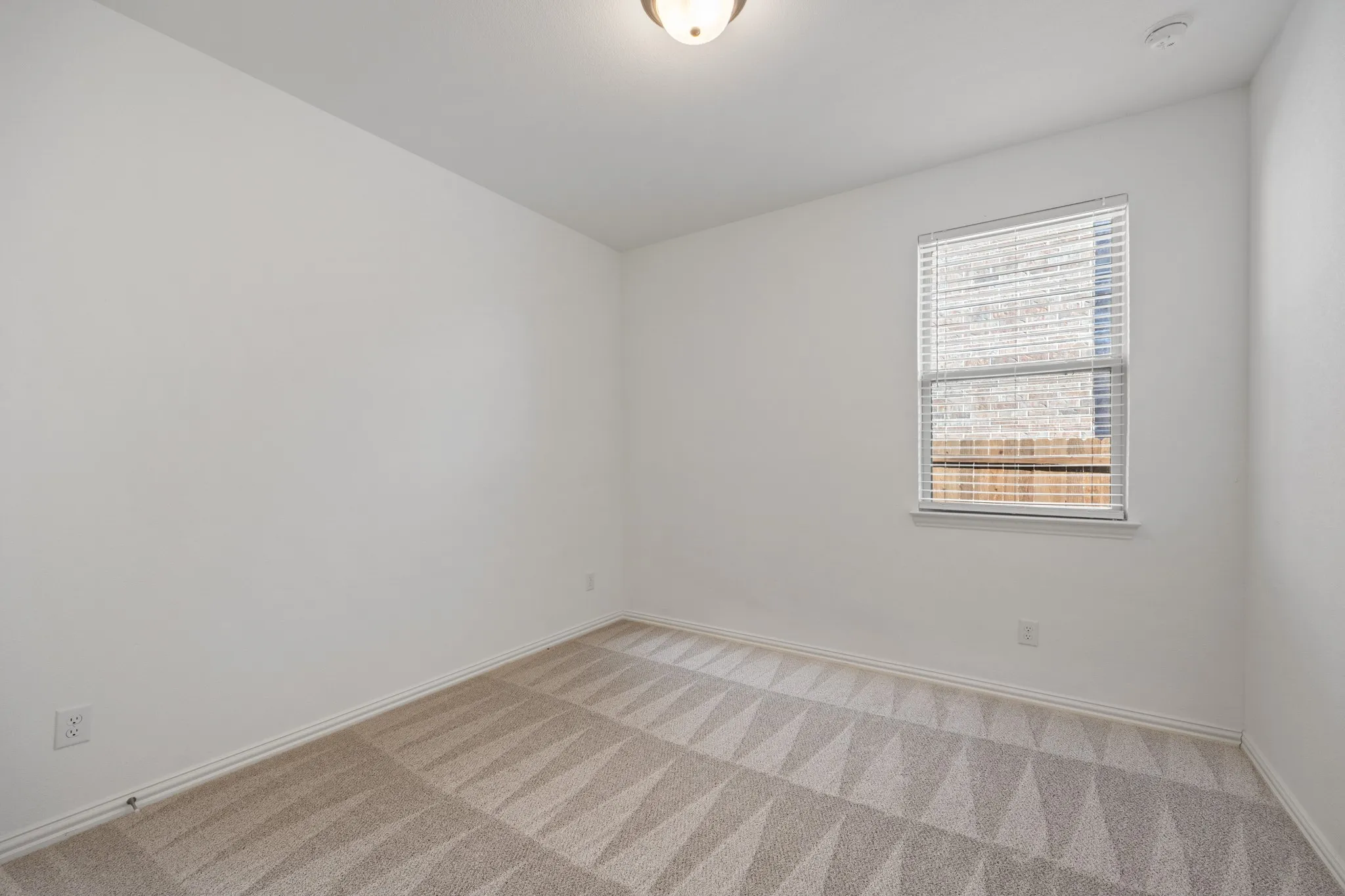 Neutral color palette, patterned carpeting, window with blinds, ceiling-mounted light fixture, white walls