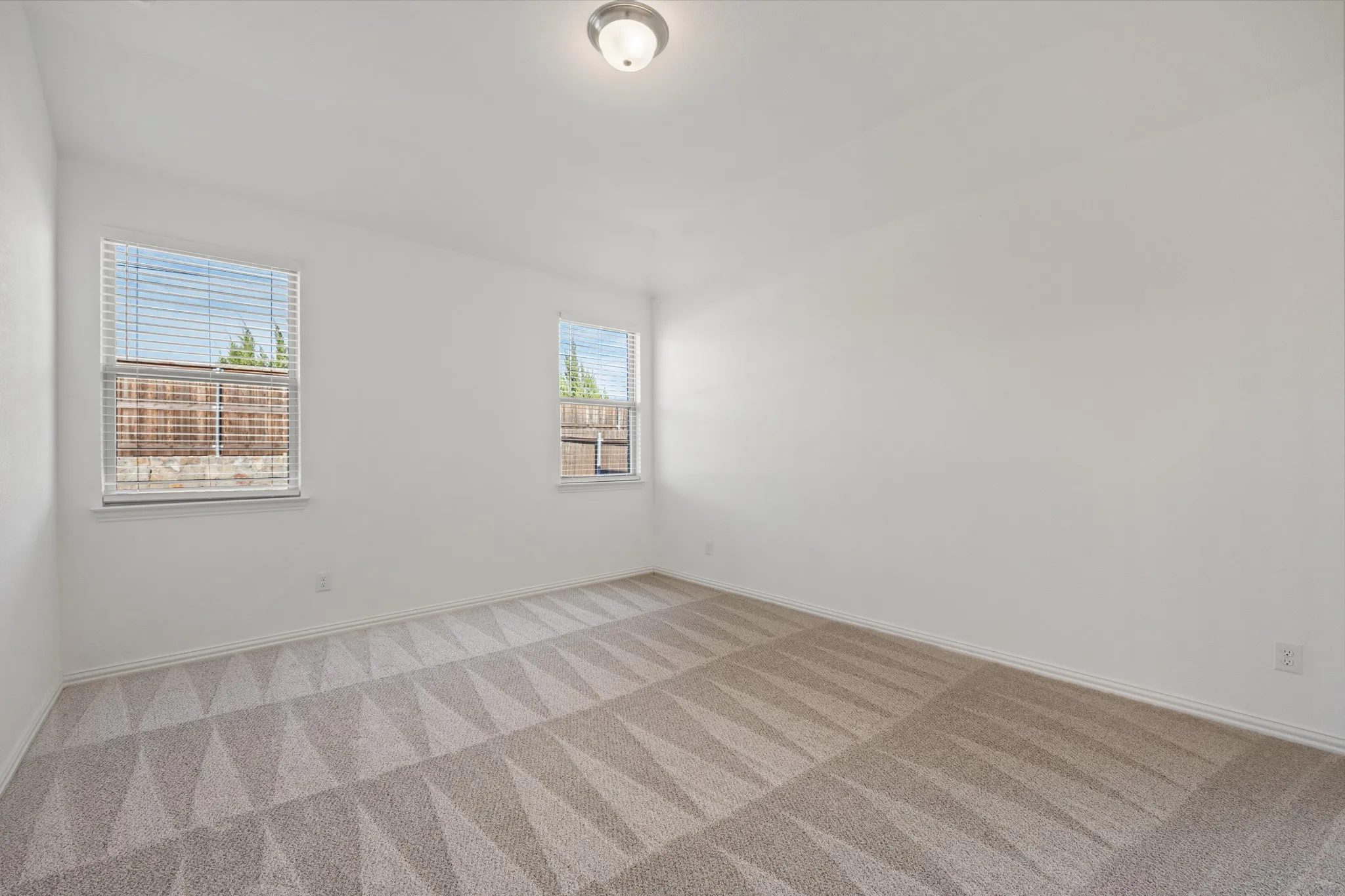 Neutral color palette with patterned carpet, two windows, and a flush mount ceiling light
