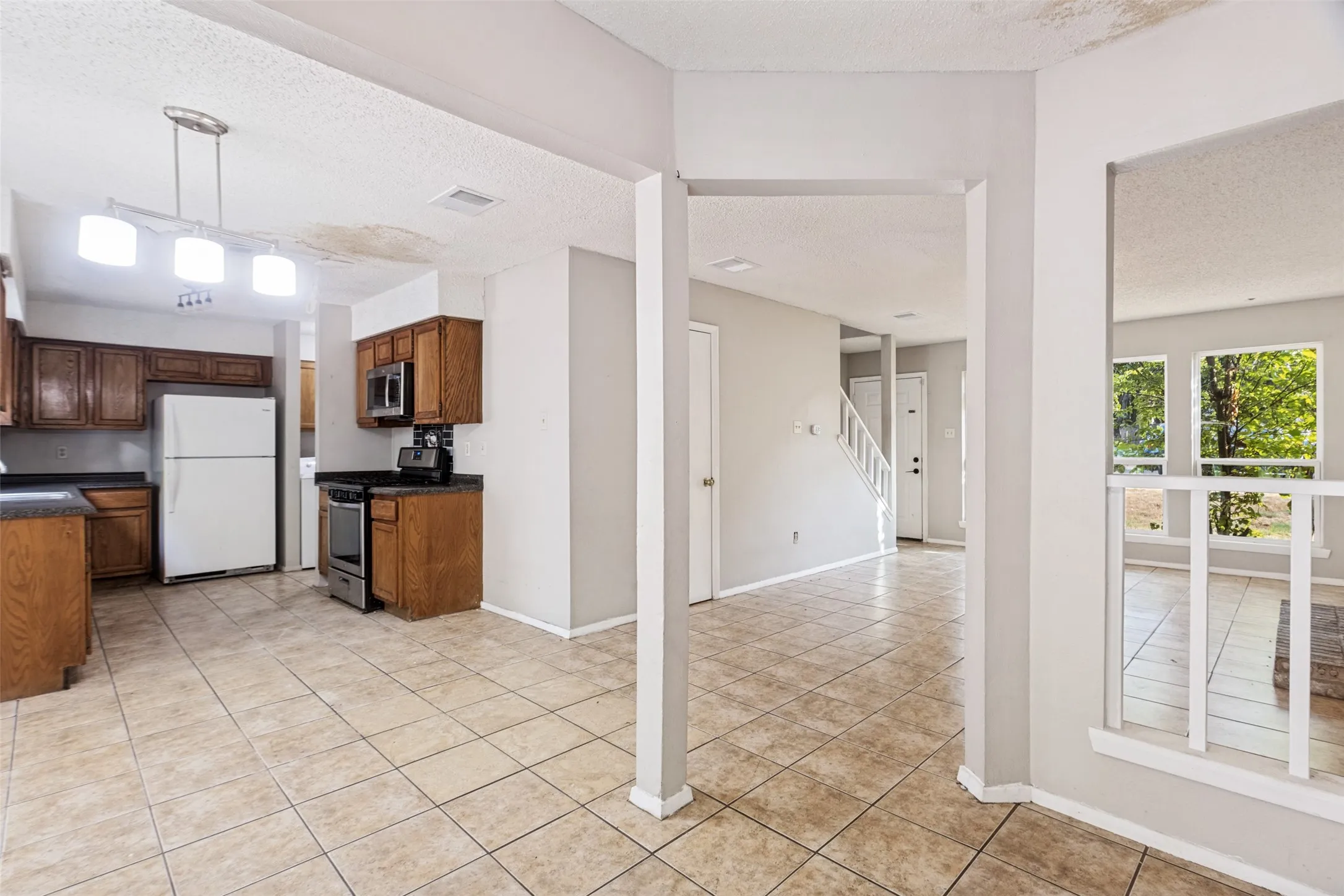 Kitchen with wood cabinetry, stainless steel appliances, and tile flooring