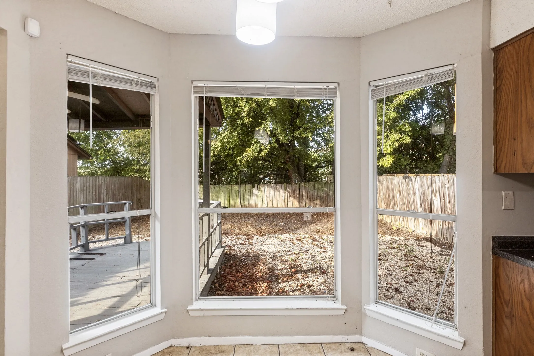 Bay window with three paneled windows, tiled flooring, wood cabinetry, and dark countertops