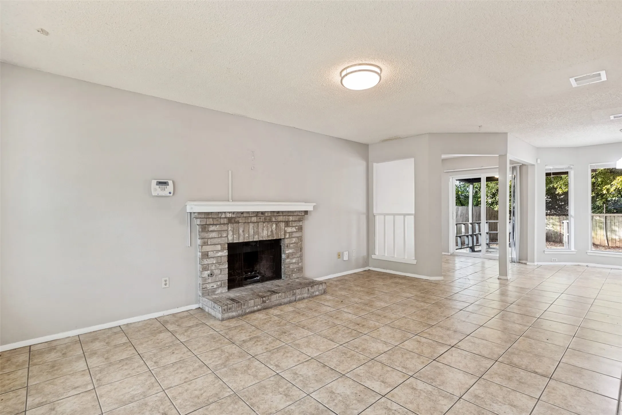 Stone brick fireplace with hearth, tile flooring, recessed lighting, and multiple windows