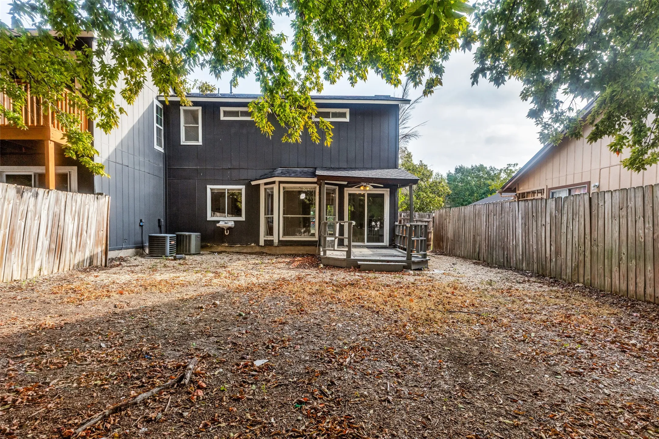 Rear exterior with a dark-painted facade, multiple windows, and a ground-level deck featuring sliding glass doors