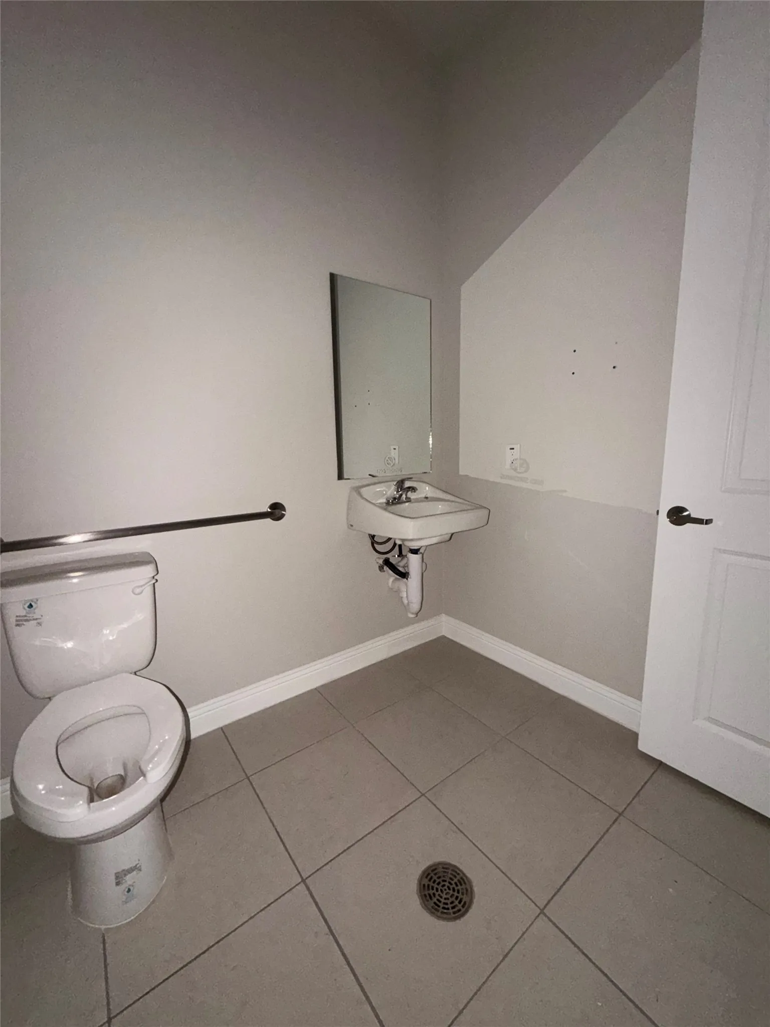 Wall-mounted sink with chrome faucet, a mirror, and a toilet