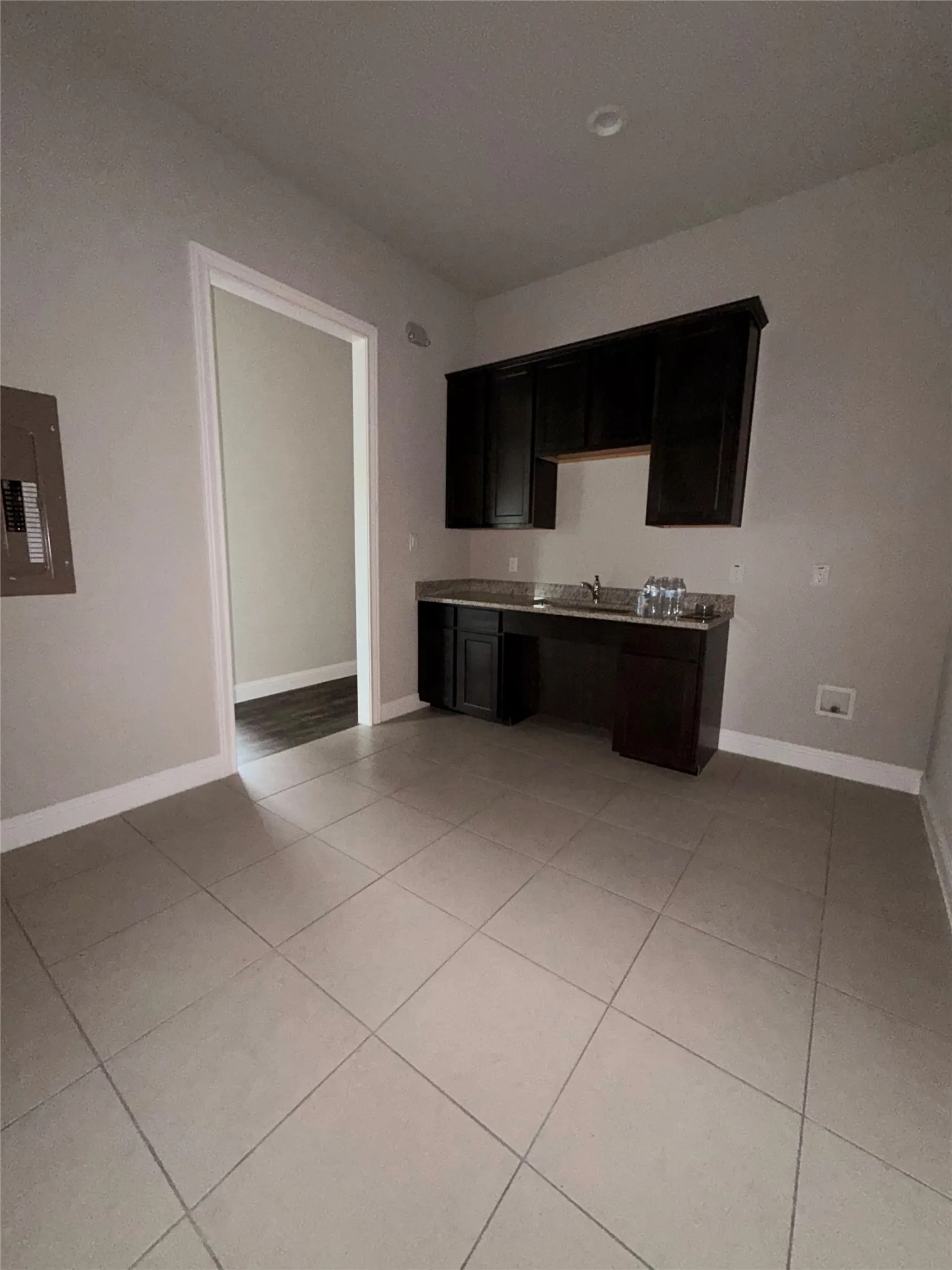 Recessed lighting illuminates the space featuring dark wood-finish cabinetry, a sink, and a countertop