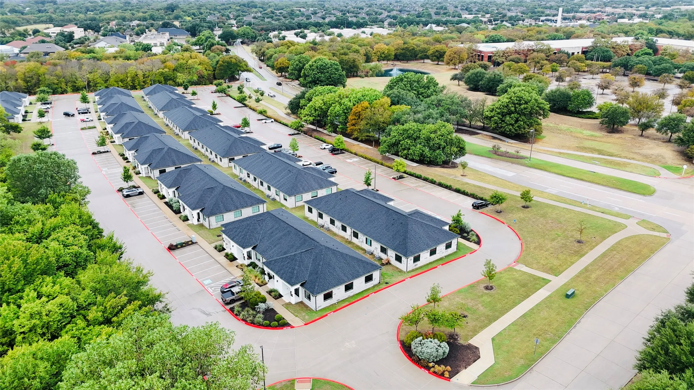 Rows of single-story buildings with dark shingle roofs, white exteriors, and individual parking spaces