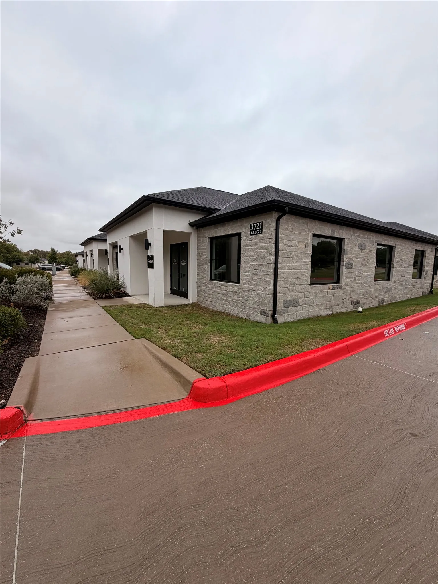 Stone veneer and stucco exterior with dark-framed windows and a dark shingled roof